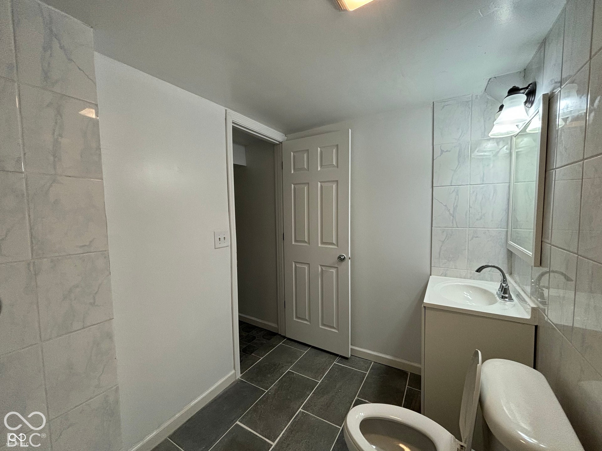 1345 Carroll White Drive, Indianapolis, IN 46219 Tiled flooring with a scattered pattern, white paneled door, and a vanity with an integrated sink