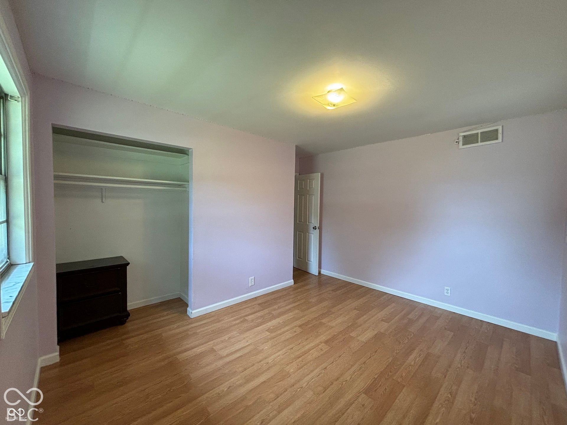 1345 Carroll White Drive, Indianapolis, IN 46219 Wood-finish flooring, overhead lighting, window with grids, and a built-in closet with shelving and hanging rod