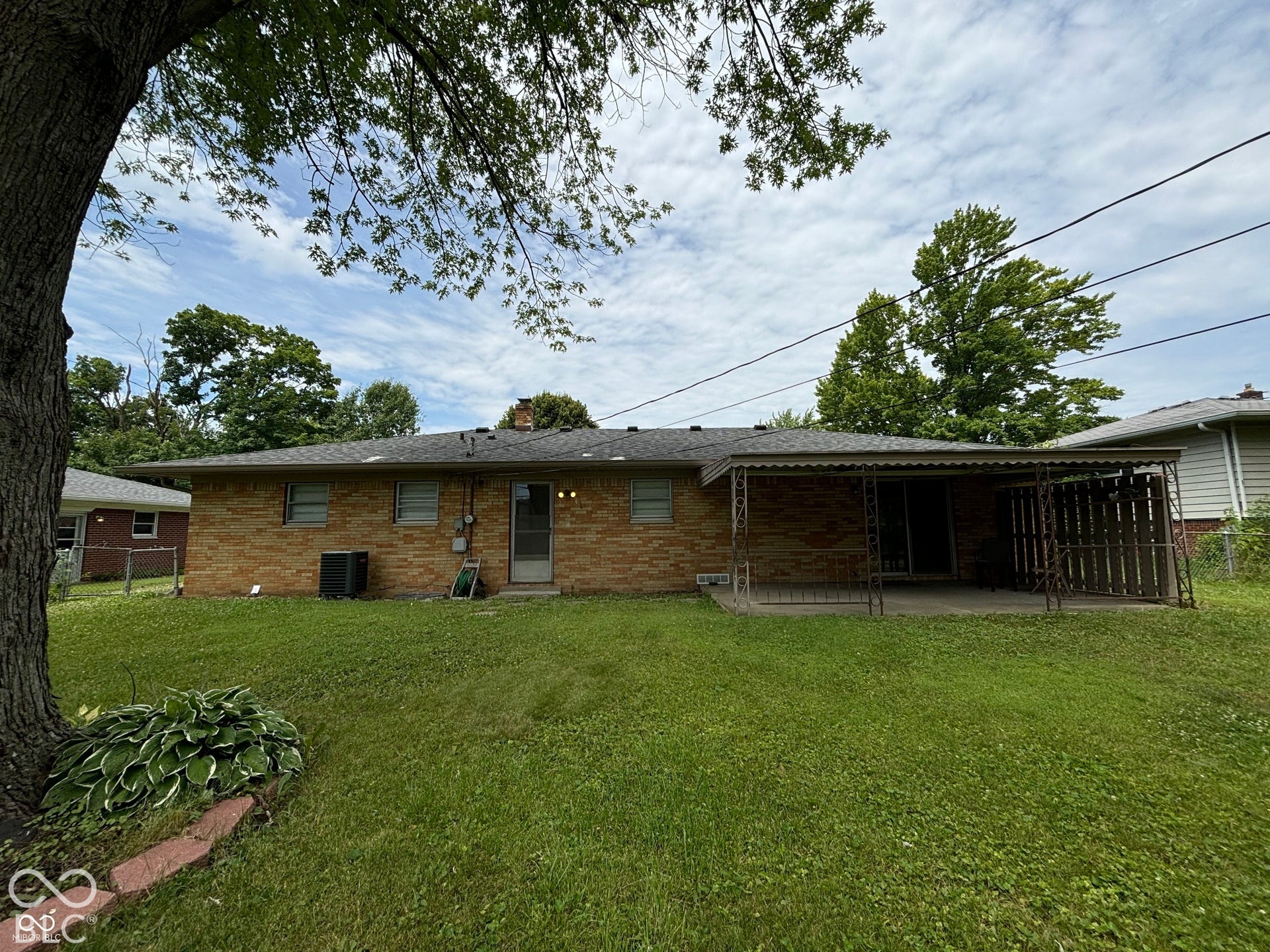 1345 Carroll White Drive, Indianapolis, IN 46219 Expansive green space featuring a brick exterior, covered patio, and mature trees