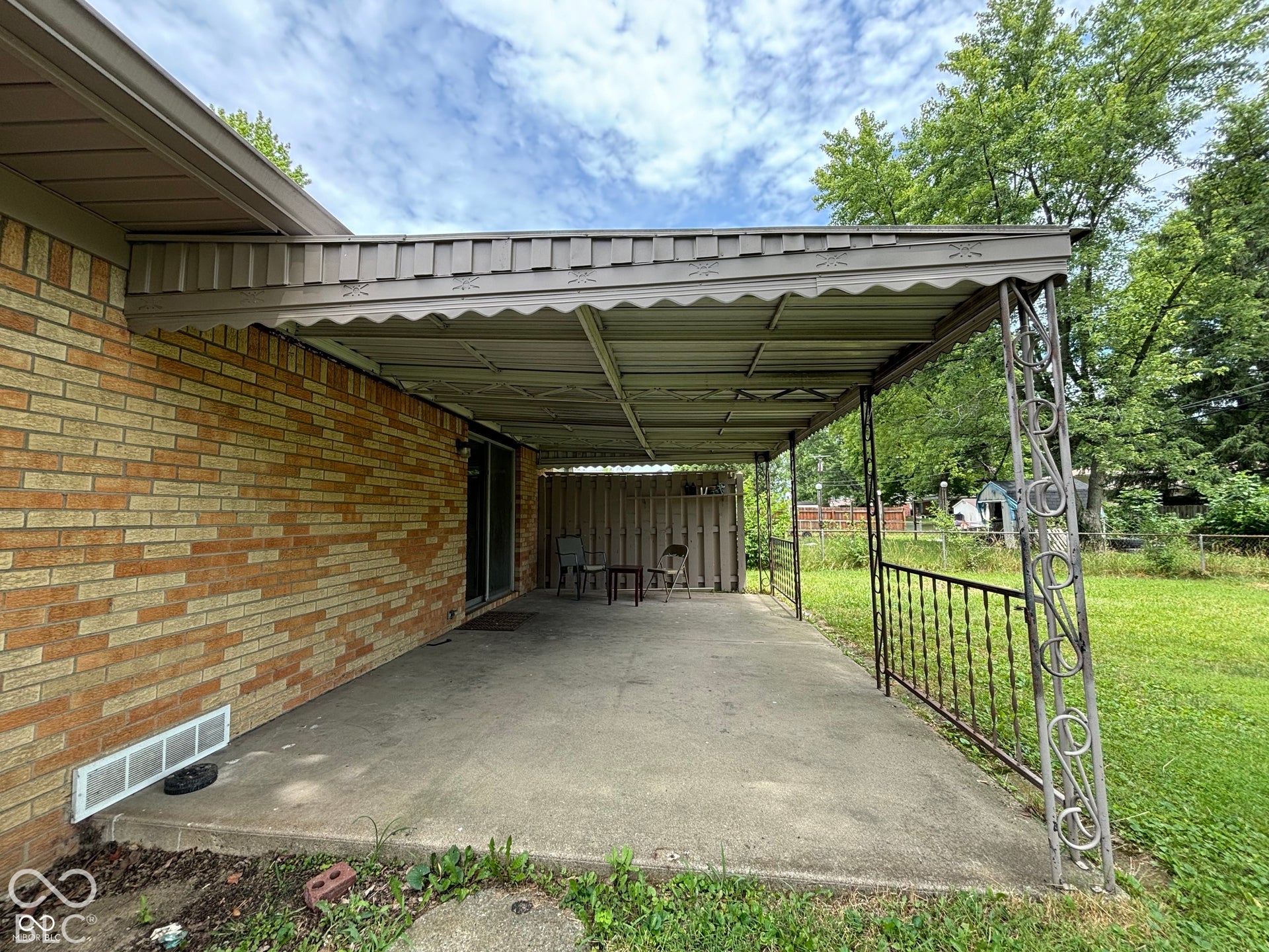 1345 Carroll White Drive, Indianapolis, IN 46219 Covered patio with a concrete surface, brick exterior, and decorative wrought iron railing