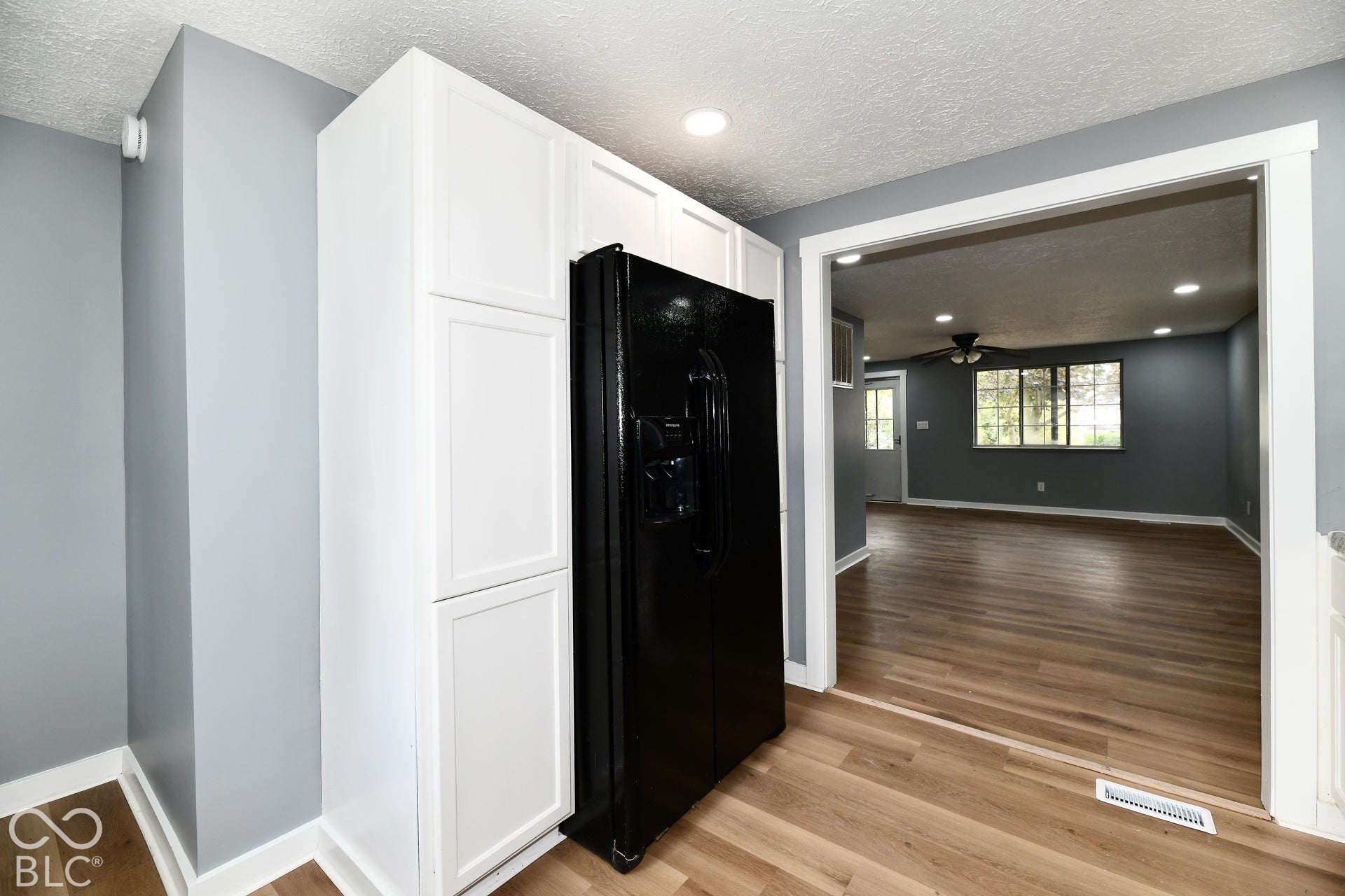 Kitchen featuring white shaker-style cabinetry, a built-in black refrigerator, recessed lighting, and wood-finish flooring