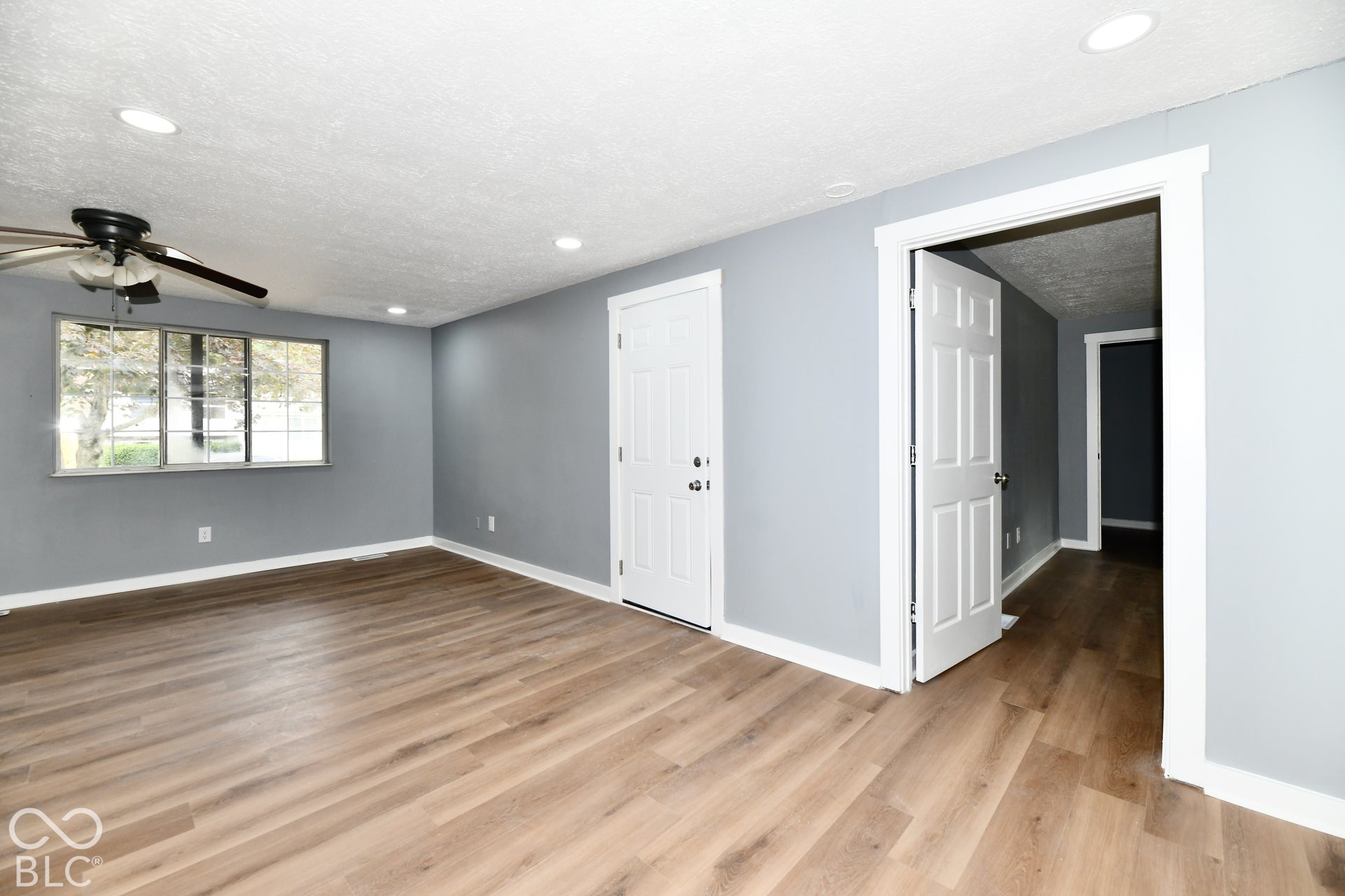 Neutral-toned interior featuring wood-finish flooring, recessed lighting, a ceiling fan, and white interior doors with casing