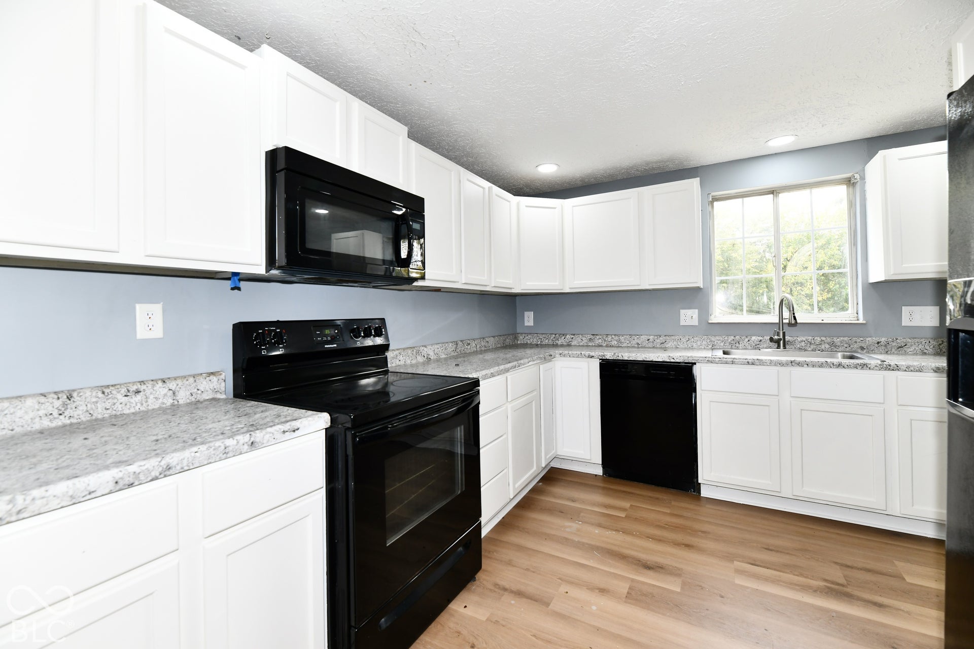Kitchen featuring white cabinetry, stone-finish countertops, black built-in appliances, recessed lighting, and wood-finish flooring