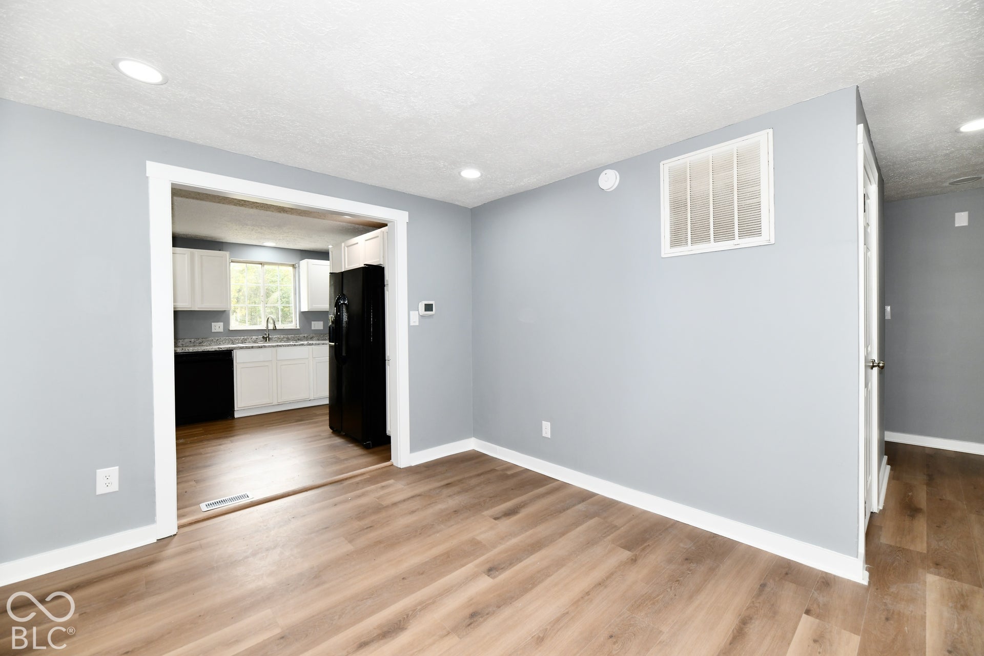 Neutral-toned interior space featuring wood-finish flooring, recessed lighting, and white door casings