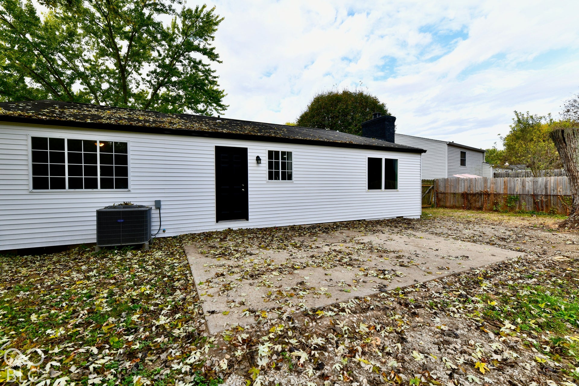 Exterior featuring white vinyl siding, a concrete patio, multi-pane windows, and a wood privacy fence