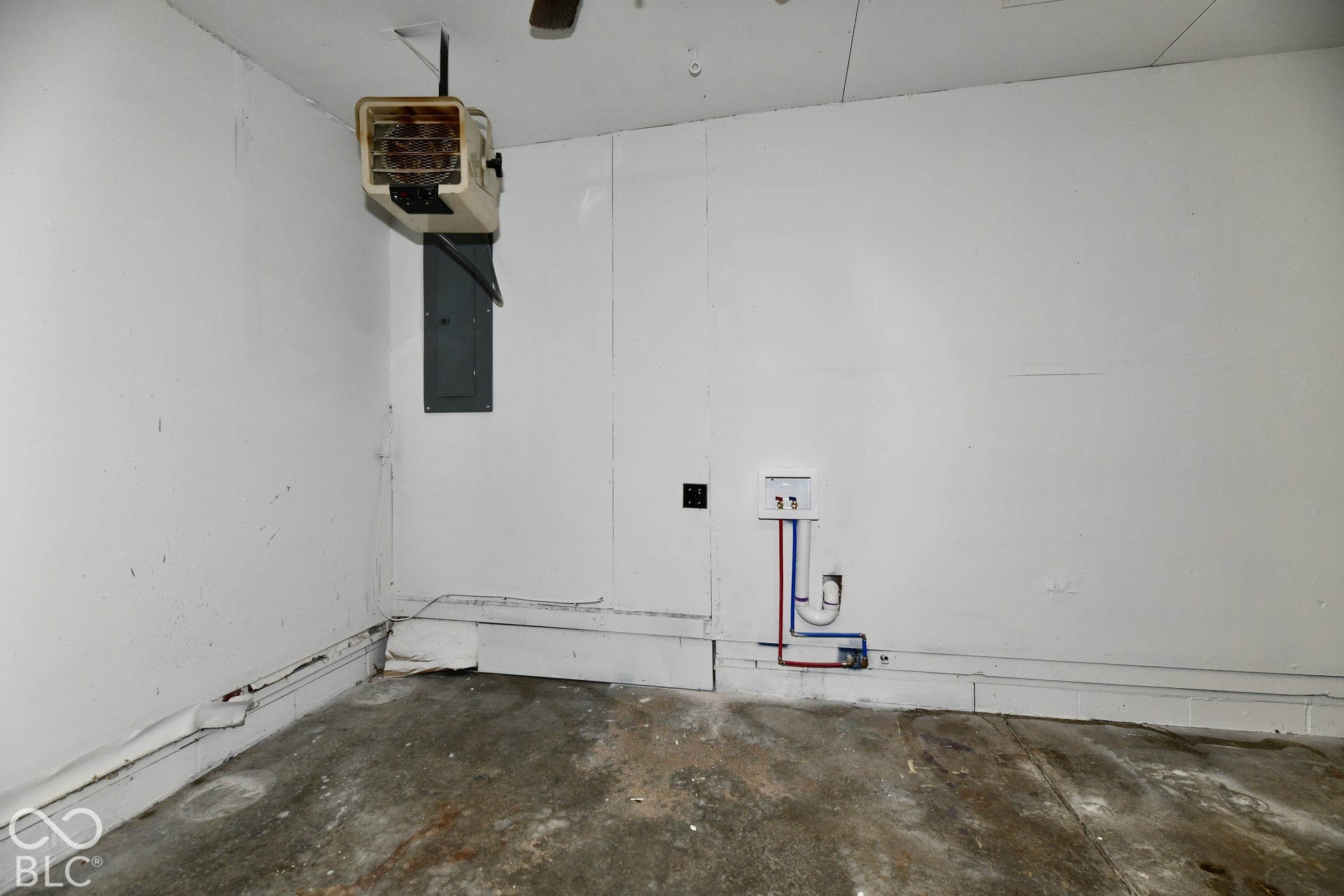 Utility area featuring a wall-mounted overhead heater, electrical panel, and dedicated plumbing connections for laundry appliances