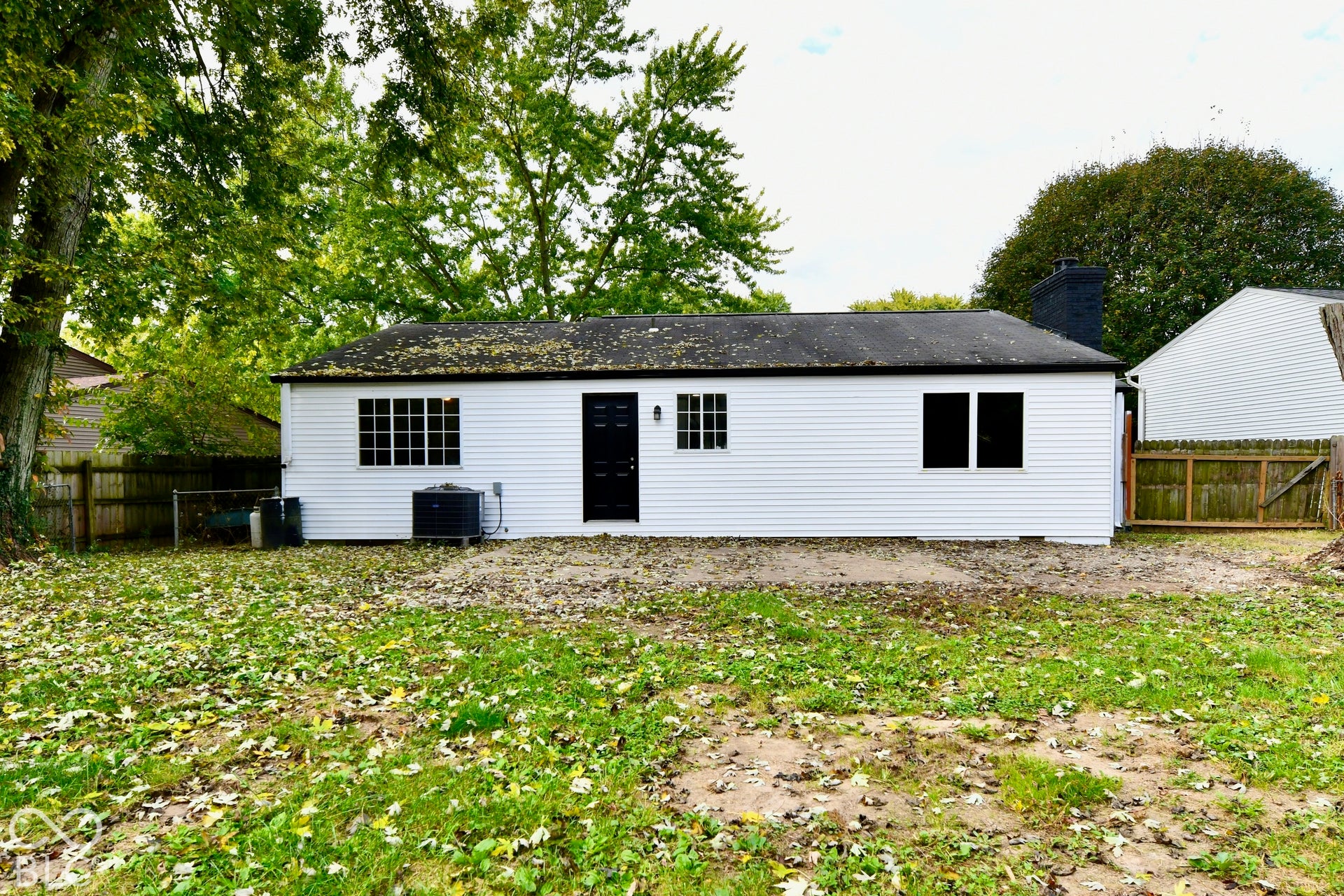 Exterior featuring white horizontal siding, dark-toned roof shingles, black painted chimney, multi-pane windows, and a black exterior door