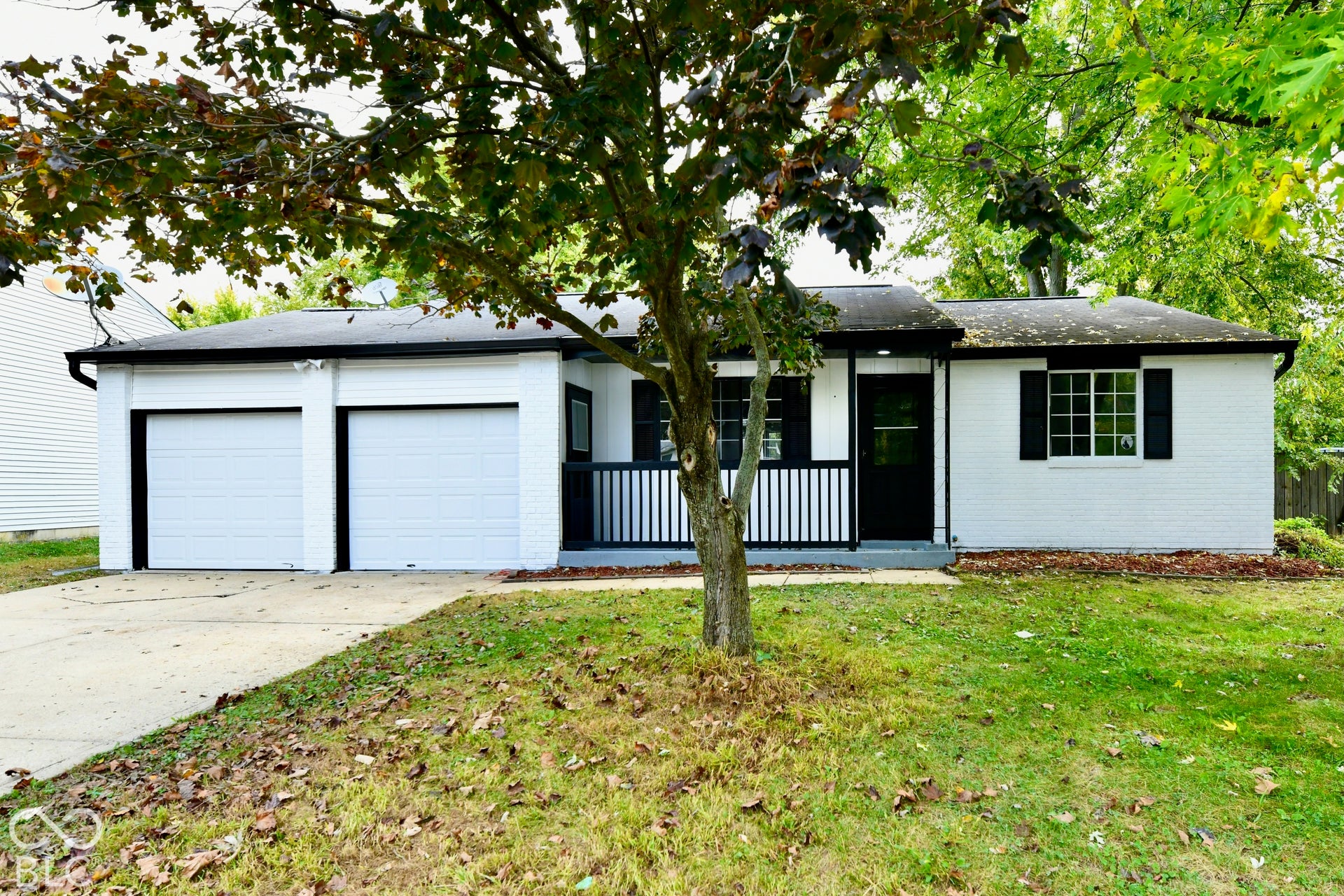 Single-story exterior featuring painted brick, a two-car garage, and a covered front porch with a railing