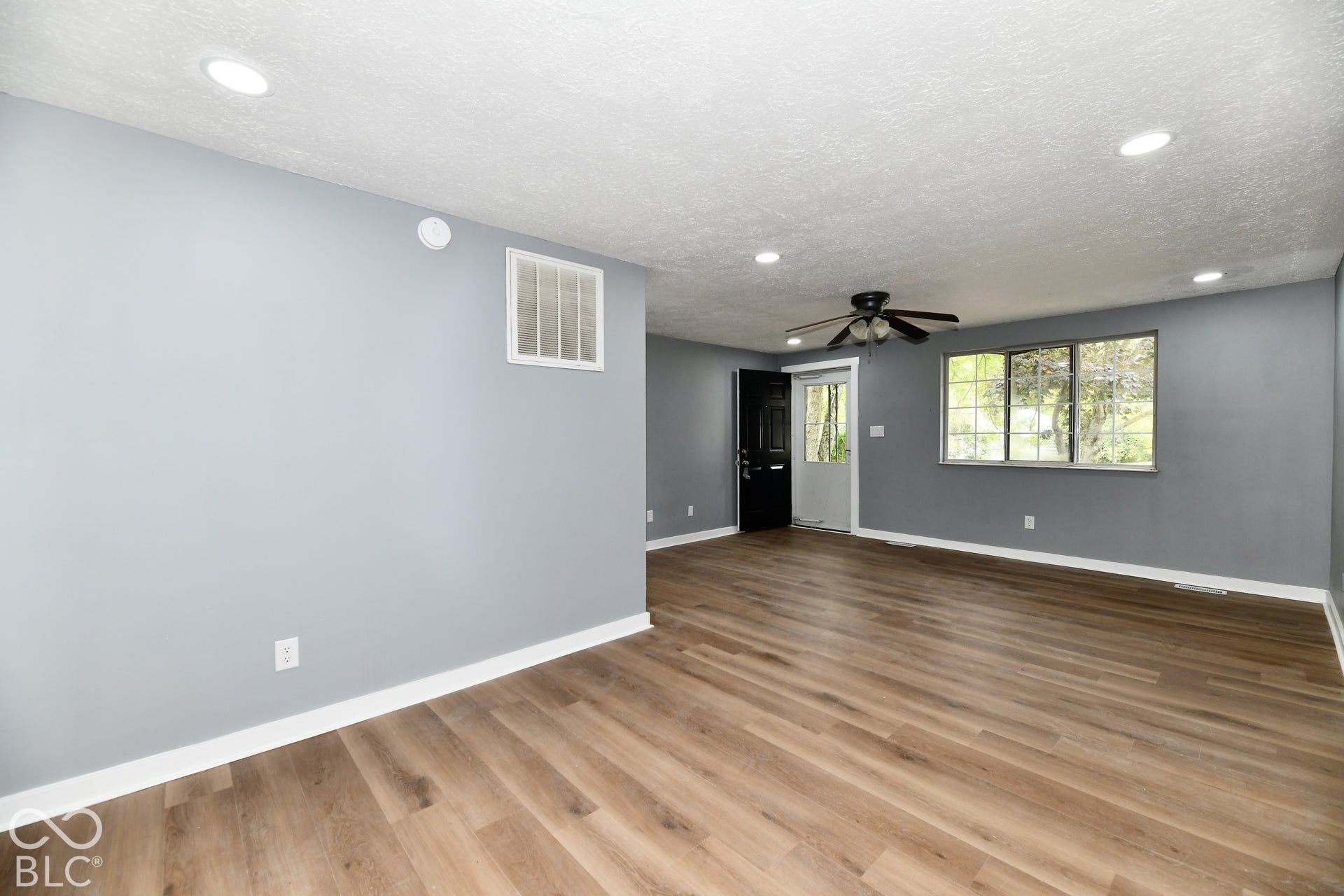 Wood-finish flooring, recessed lighting, ceiling fan with light fixture, and large windows