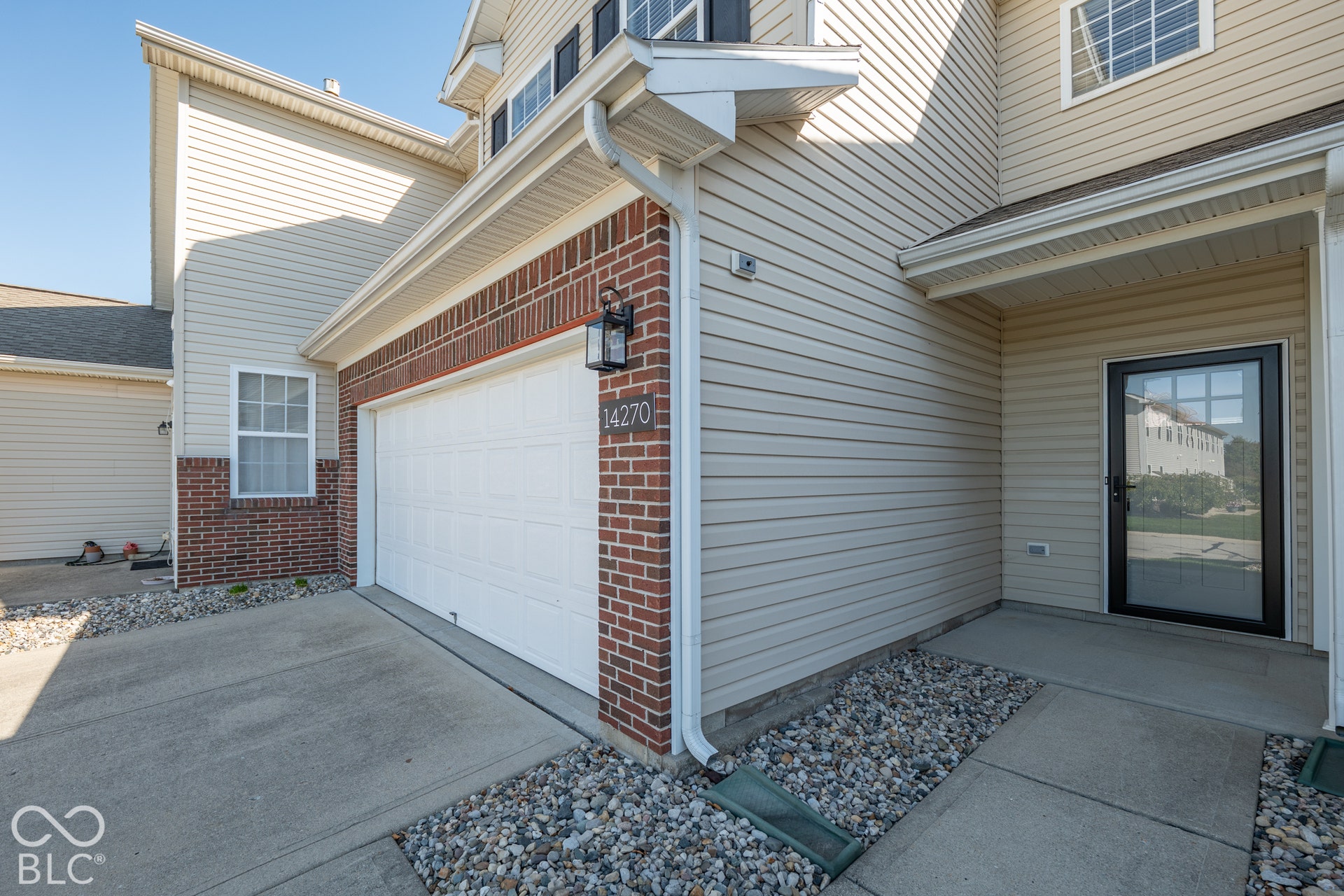 Attached garage with exterior lighting and brick veneer accents