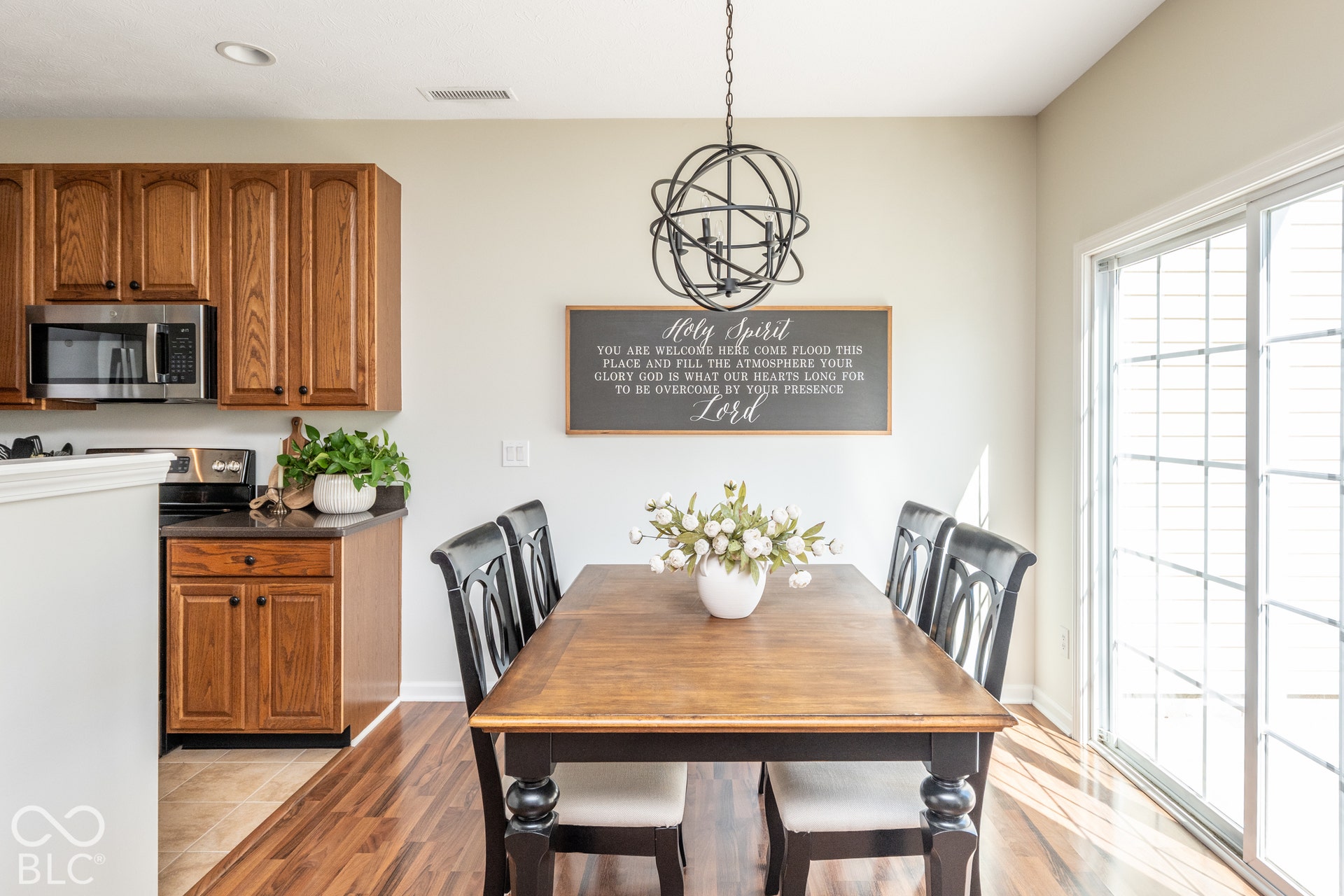 Wood-finish flooring, oak cabinetry, stainless steel microwave, stainless steel range, and sliding glass door