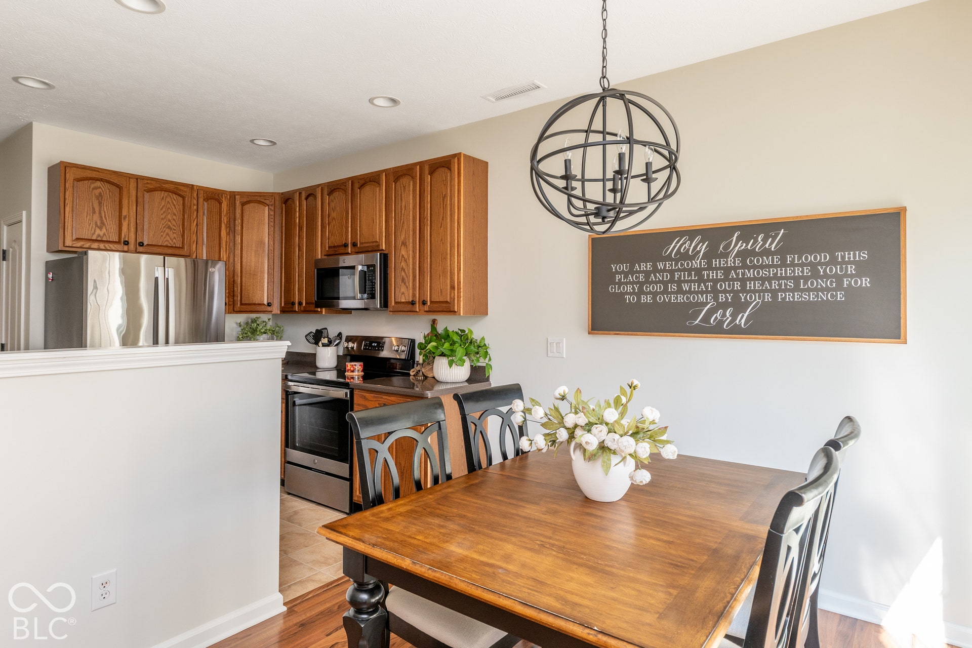 Kitchen featuring wood cabinetry, stainless steel appliances, recessed lighting, and a dining area with a contemporary orb chandelier