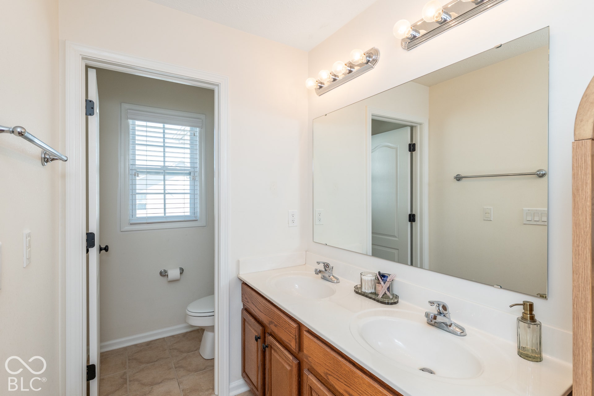 Dual vanity with white countertop, chrome fixtures, and a large mirror