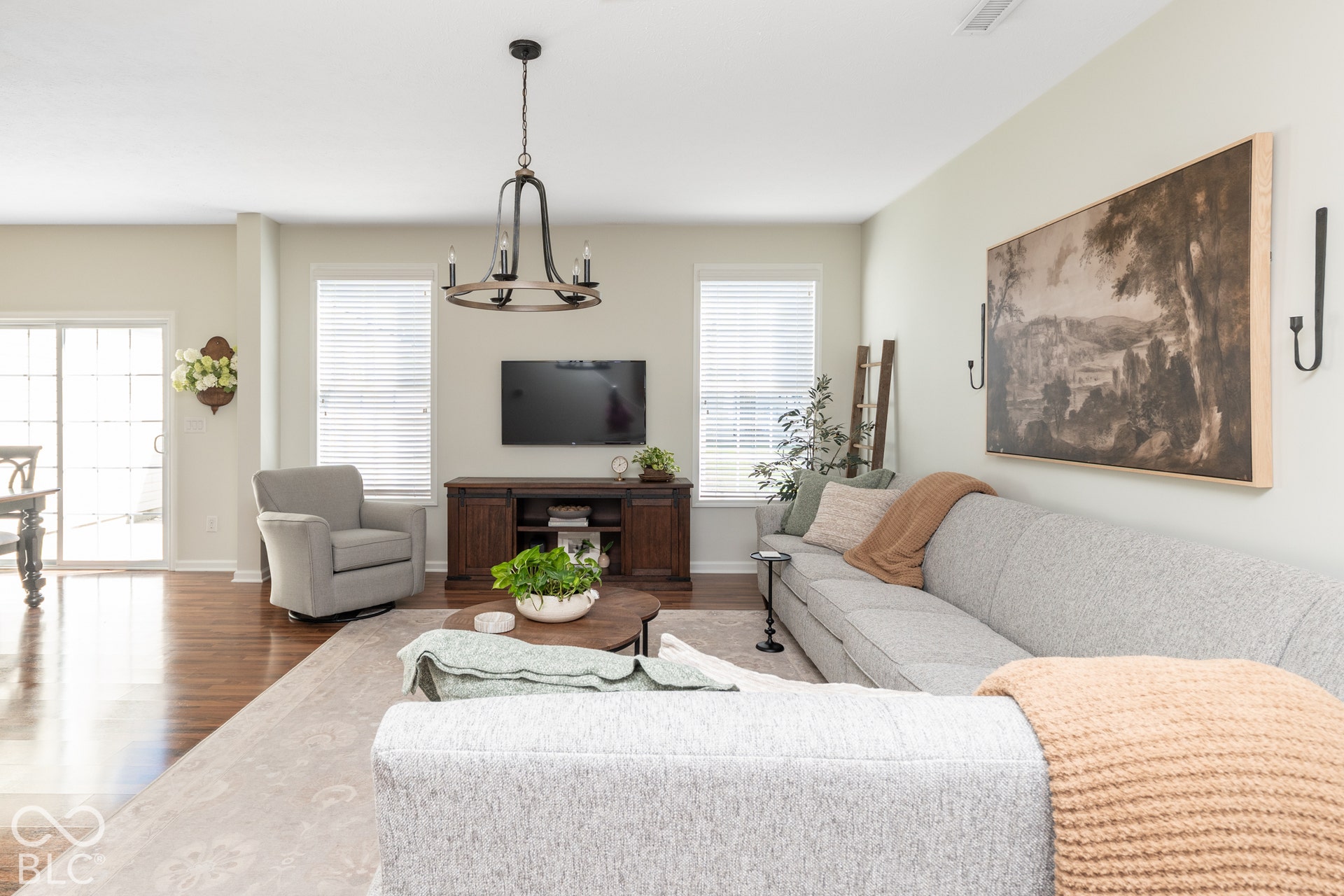 Hardwood-finish flooring, sliding glass patio doors, and multiple windows illuminate this living area