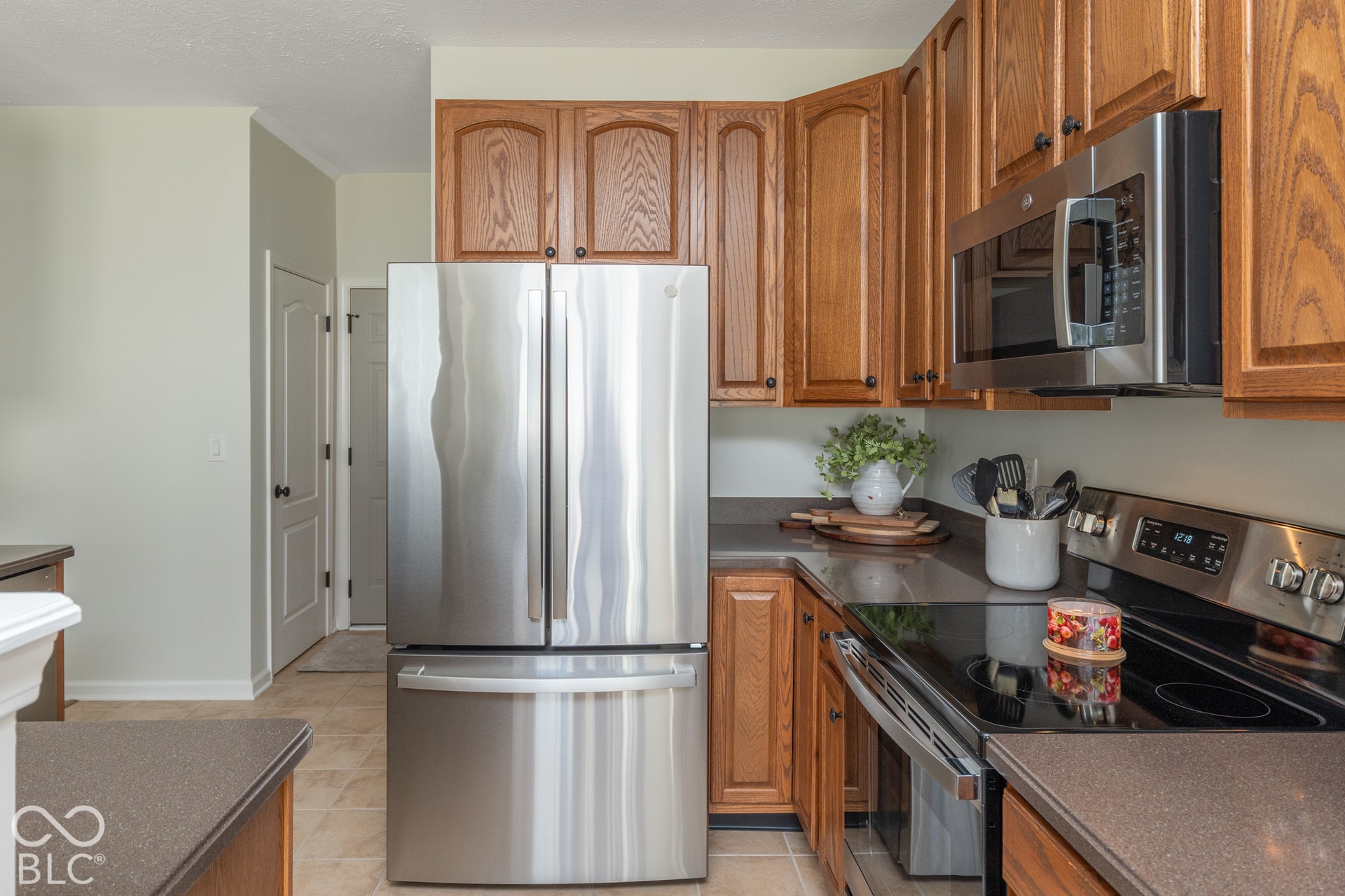 Kitchen featuring wood cabinetry, stainless steel appliances, dark countertops, and tile flooring