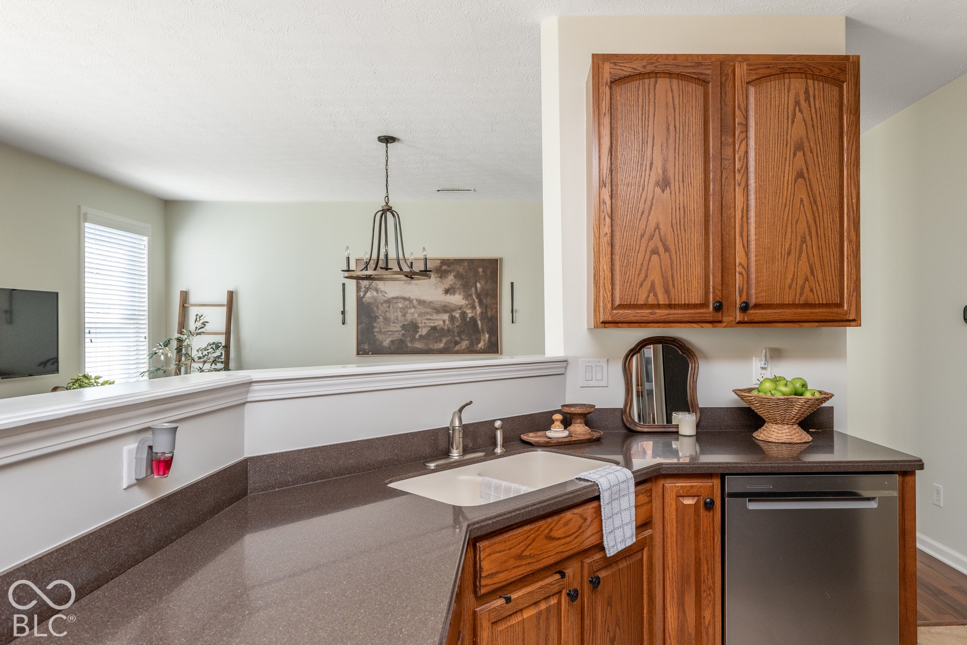 Wood-finish cabinetry, integrated stainless steel dishwasher, and a single basin sink with a chrome faucet