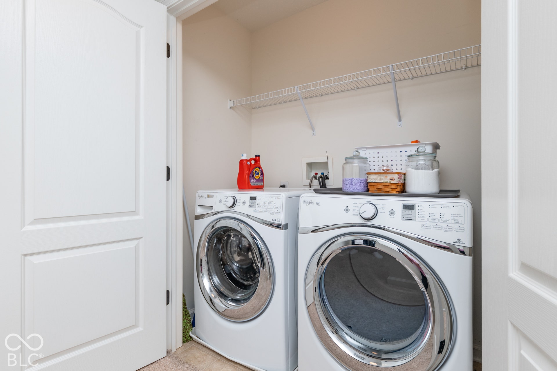 Utility space featuring light-toned walls, a white wire shelf, and a light-toned flooring