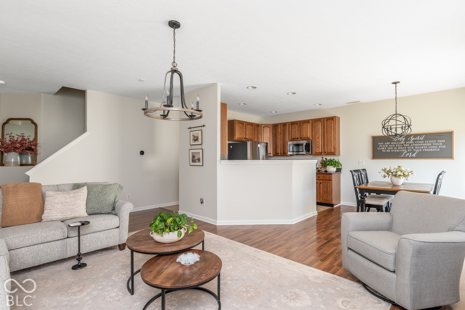 Open-concept living space featuring wood-finish flooring, a kitchen with wood cabinetry, and a dining area with a chandelier