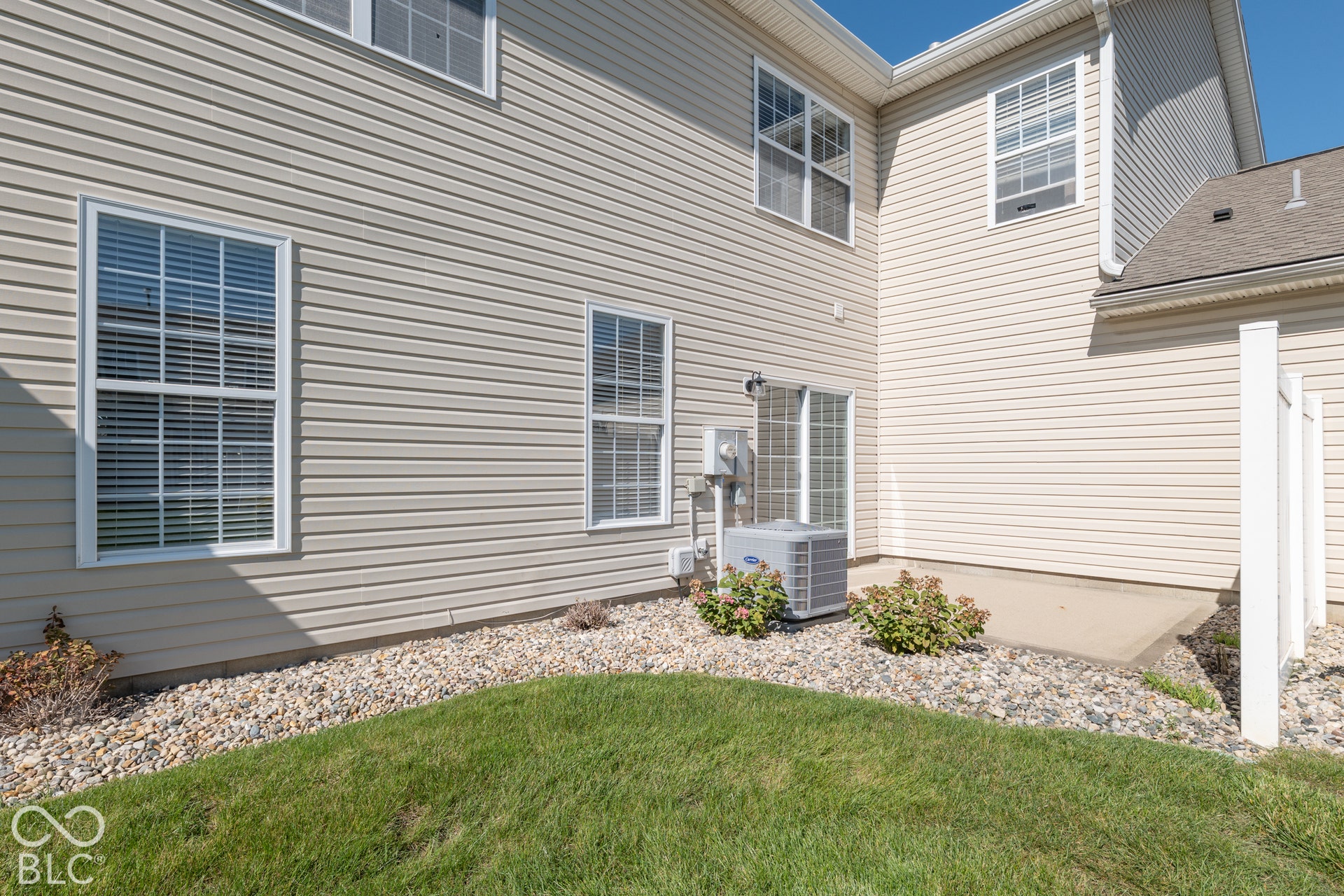 Exterior siding, multiple windows, compact patio, and gravel landscaping