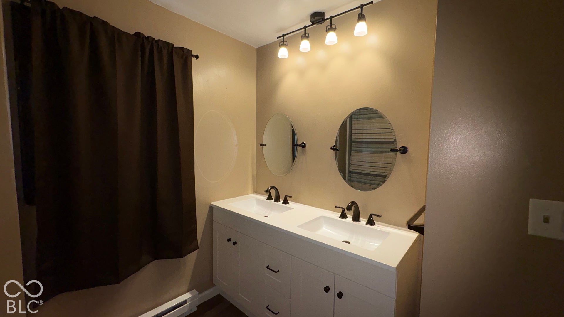 402 E Jackson Street, Farmland, IN 47340 Dual vanity with integrated sinks, white cabinetry, dark hardware, and individual oval mirrors