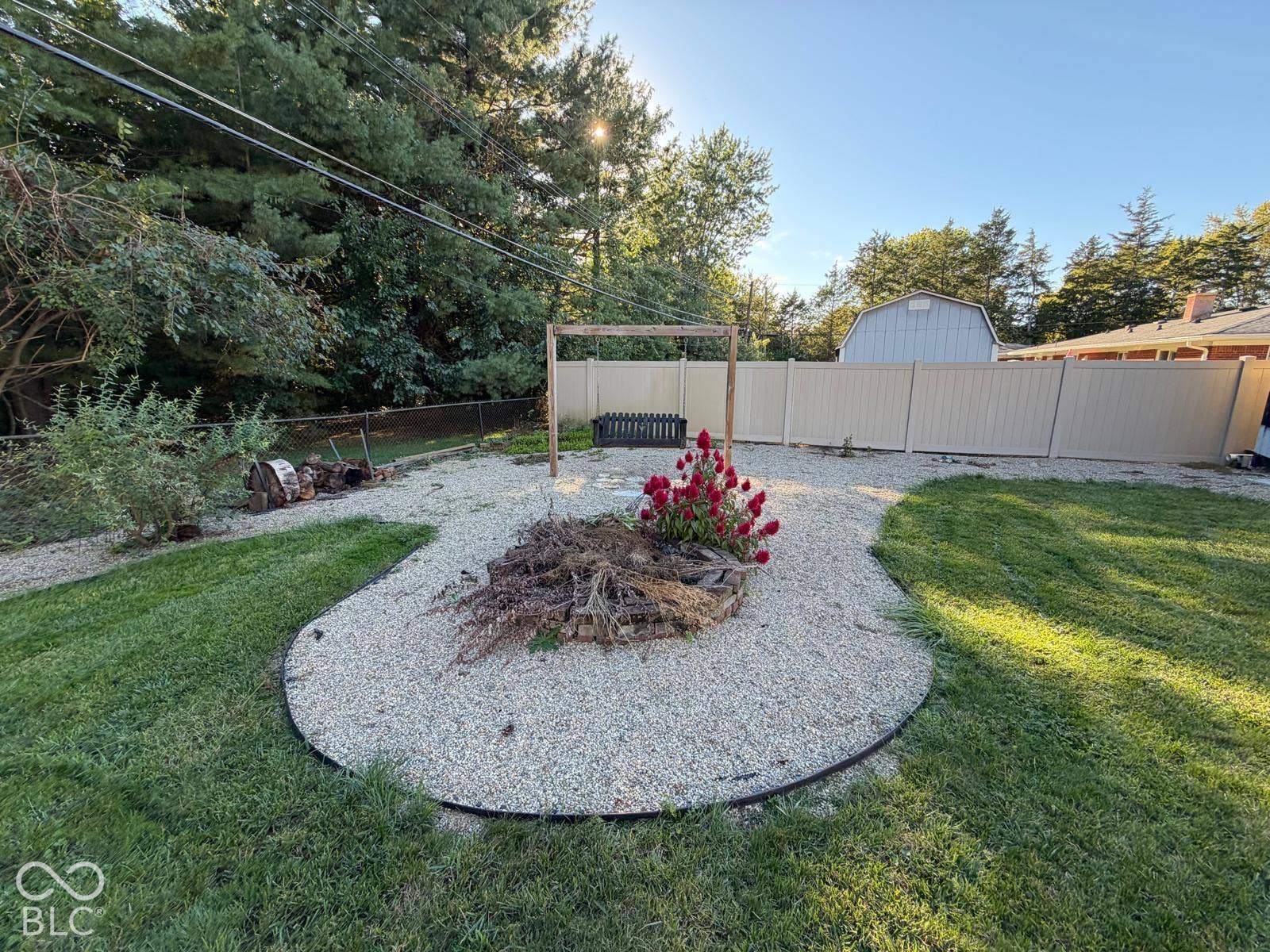 2819 E Edgewood Avenue, Indianapolis, IN 46227 Expansive backyard featuring a gravel fire pit area with a decorative plant, manicured lawn, and privacy fencing