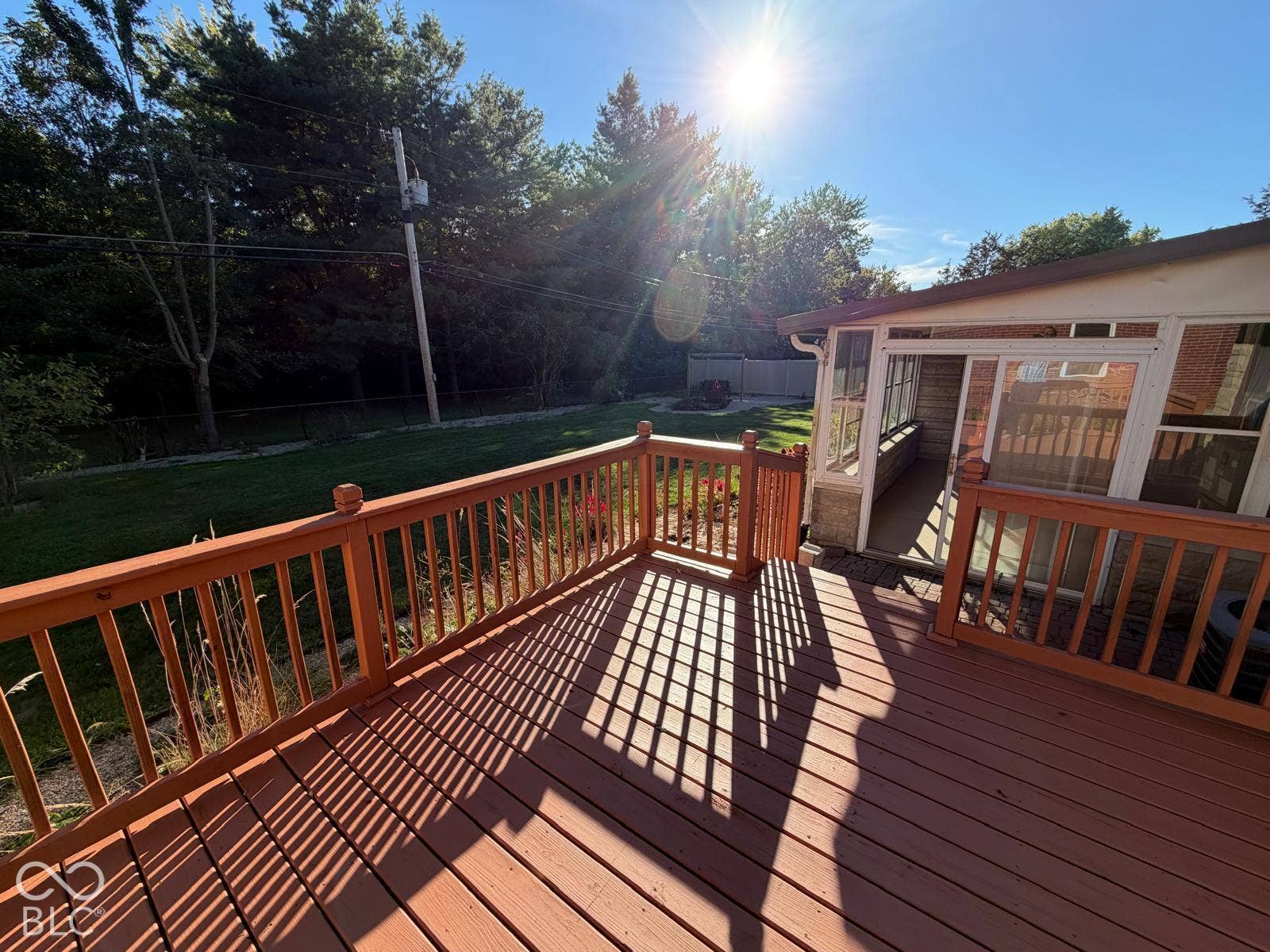 2819 E Edgewood Avenue, Indianapolis, IN 46227 Expansive wood-finish deck with railing, offering access to an enclosed porch with sliding glass doors