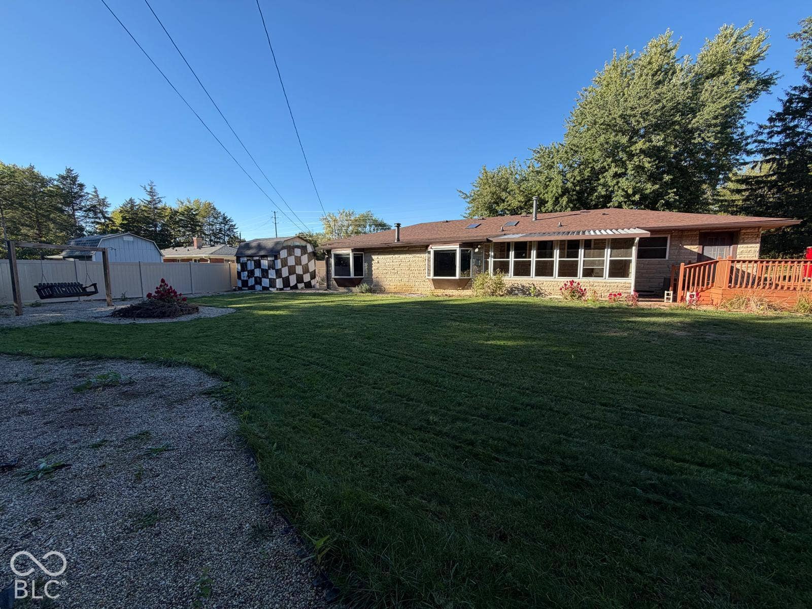 2819 E Edgewood Avenue, Indianapolis, IN 46227 Expansive green lawn, enclosed sunroom with multiple windows, brick exterior, and a wooden deck