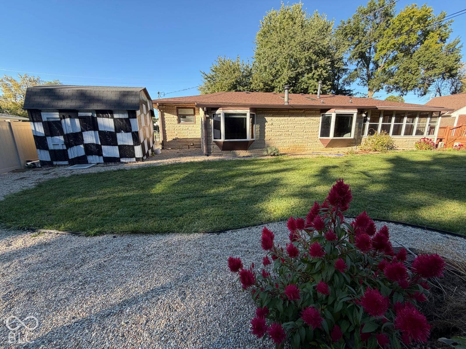 2819 E Edgewood Avenue, Indianapolis, IN 46227 Expansive lawn with a gravel border, mature trees, and a checkerboard-patterned shed