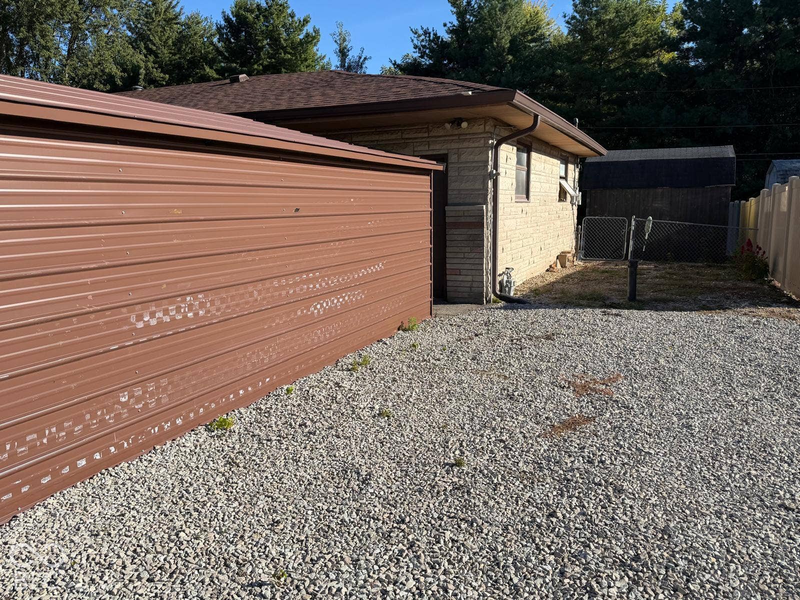 2819 E Edgewood Avenue, Indianapolis, IN 46227 Gravel driveway leading to a metal-sided utility structure and a brick-sided building with a shingle roof