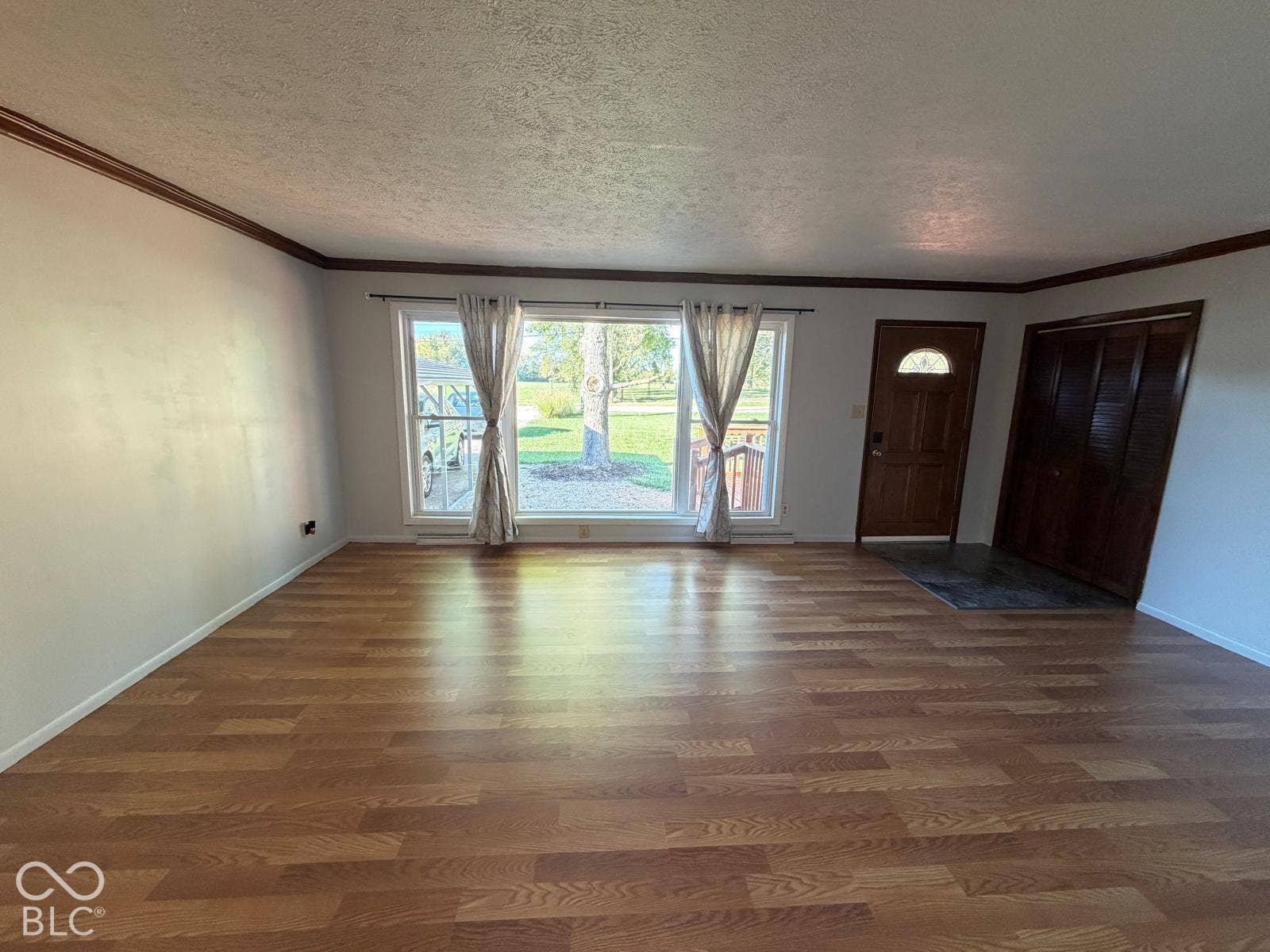 2819 E Edgewood Avenue, Indianapolis, IN 46227 Wood-finish flooring, white walls, dark wood trim, large window with natural light, and a wood entry door with an arched lite