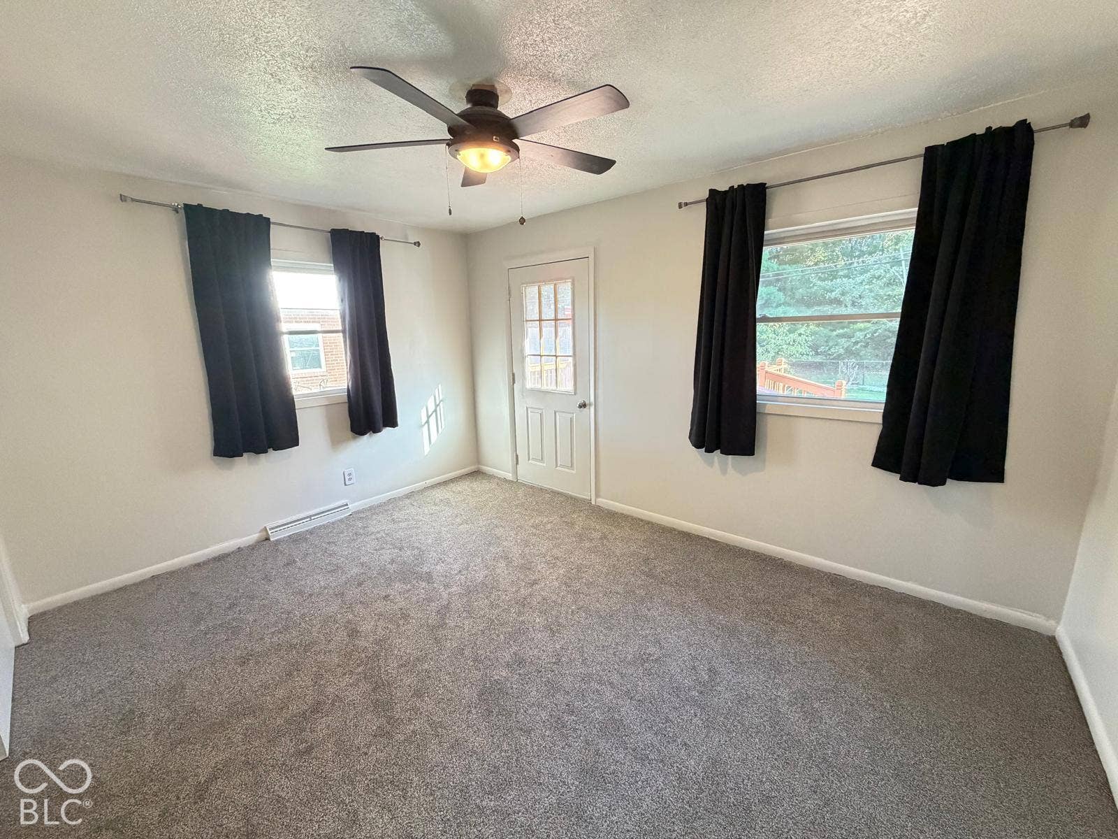 2819 E Edgewood Avenue, Indianapolis, IN 46227 Carpeted room featuring a ceiling fan with integrated lighting, two windows with curtain rods, and a door with glass panels