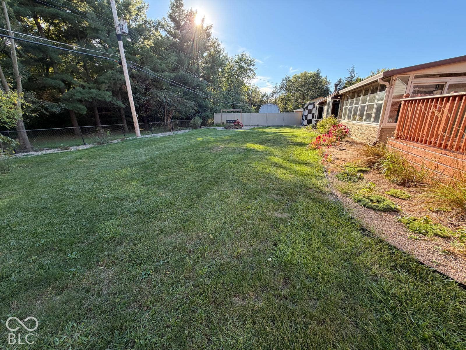 2819 E Edgewood Avenue, Indianapolis, IN 46227 Expansive lawn space with mature perimeter trees, complemented by a white privacy fence and a brick-sided structure