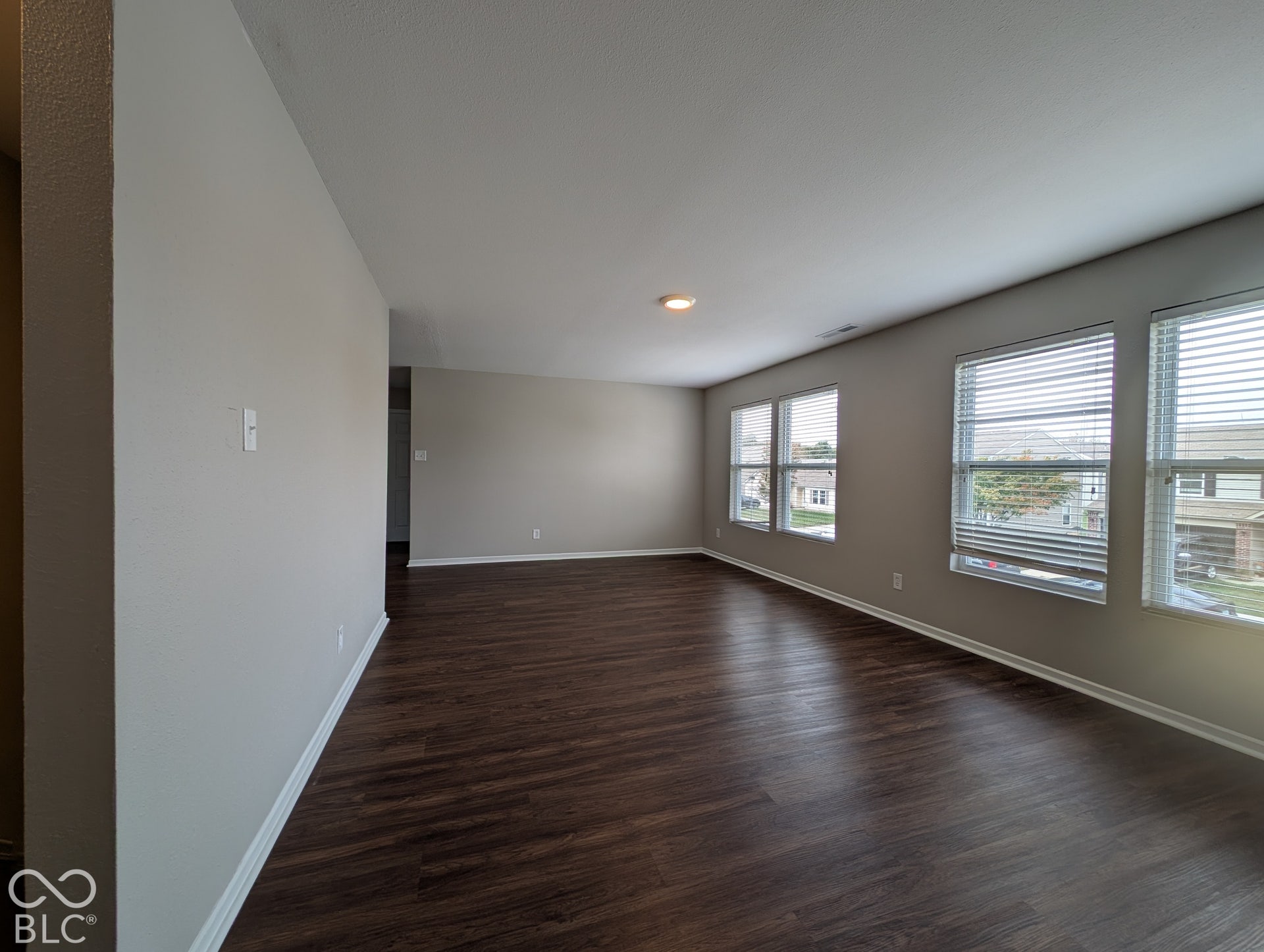 Wood-finish flooring, multiple windows with blinds, recessed lighting, and light gray wall color