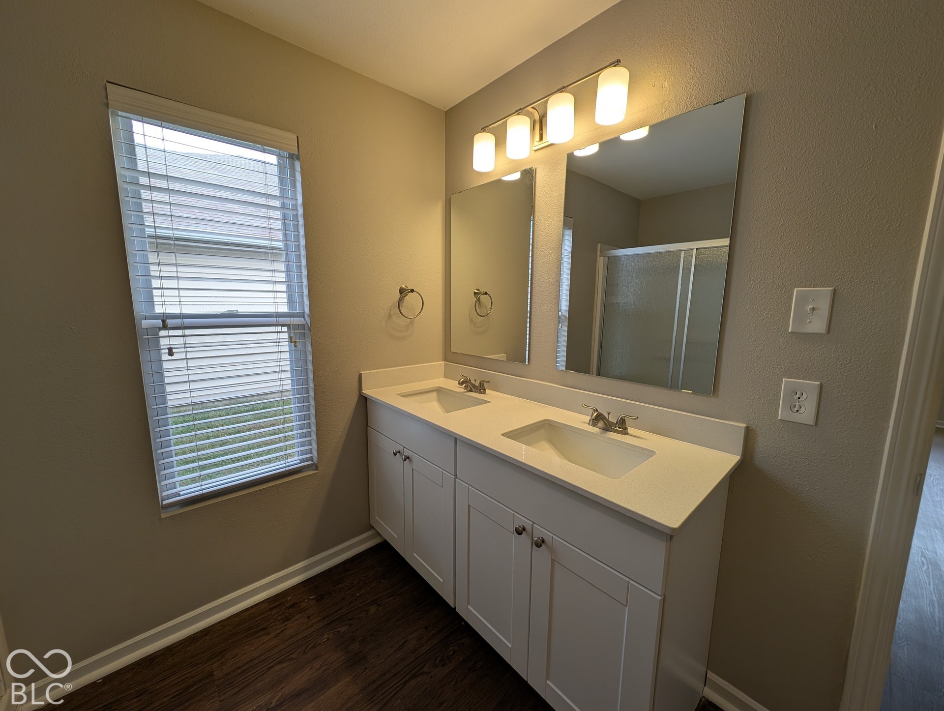 Dual vanity with integrated sinks, white cabinetry, and a full-width mirror with overhead lighting