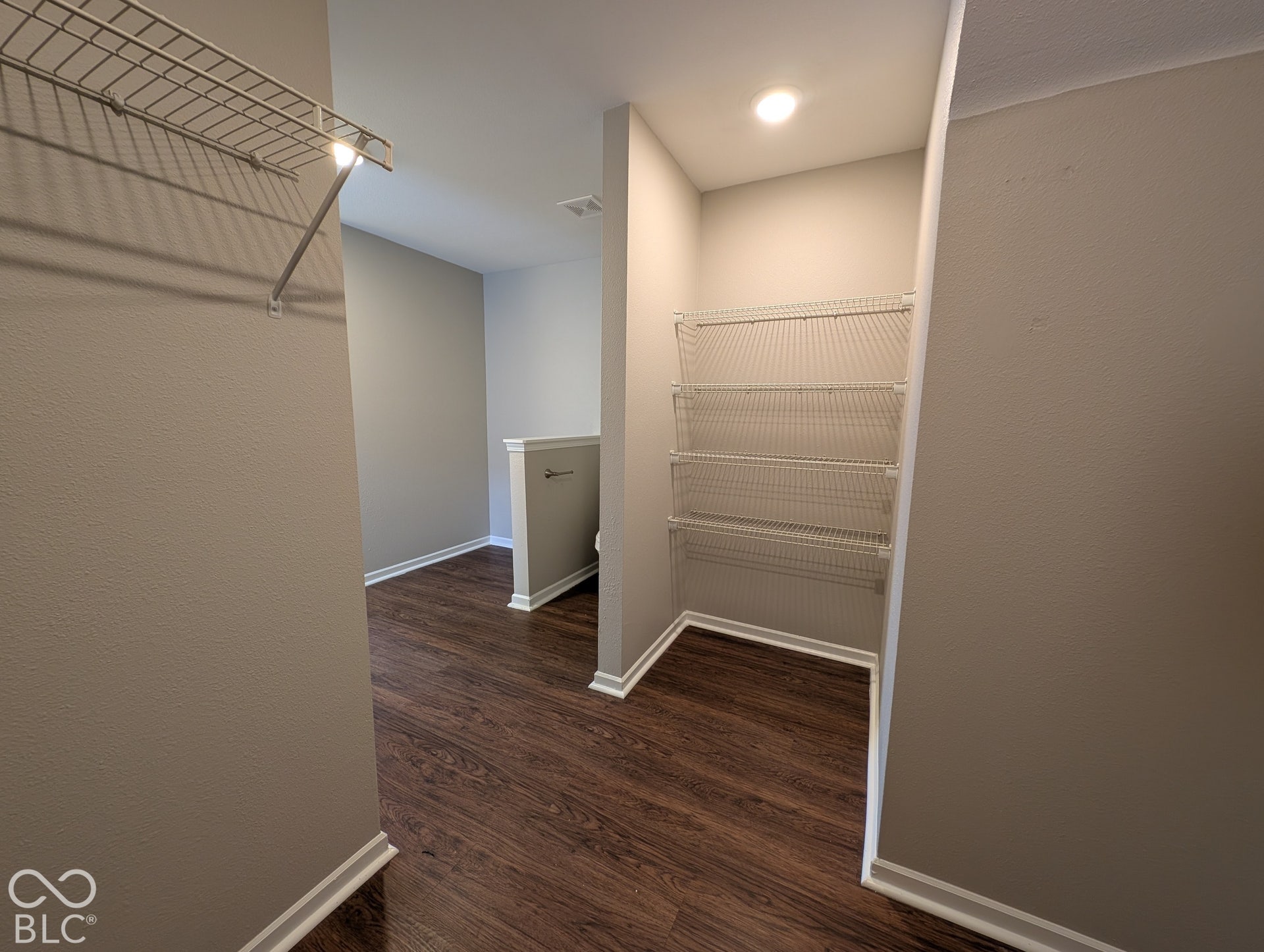 Wood-finish flooring, built-in wire shelving, recessed lighting, white baseboards, and neutral wall paint