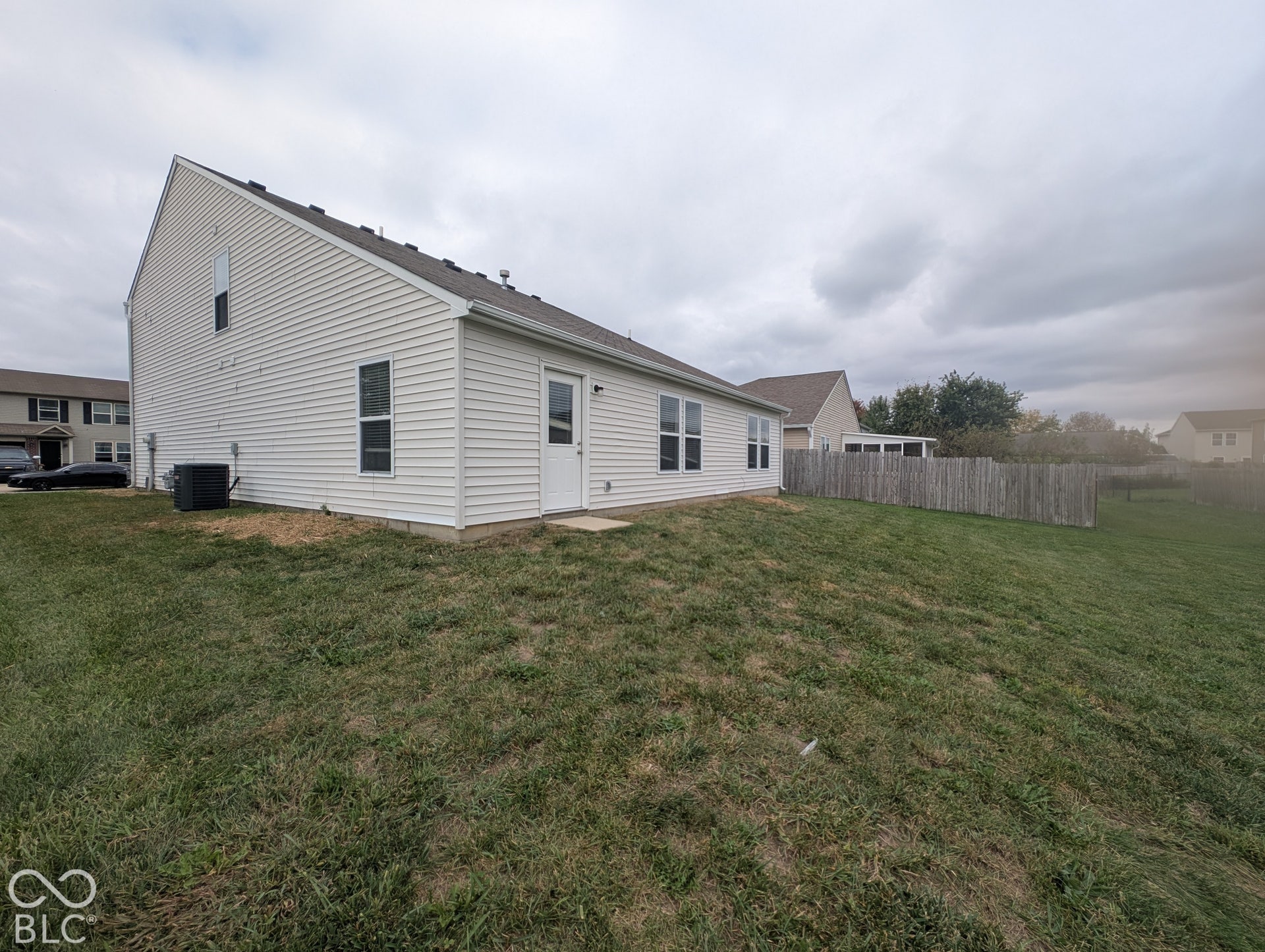 Exterior featuring white vinyl siding, multiple windows, a rear entry door, and a wooden fence