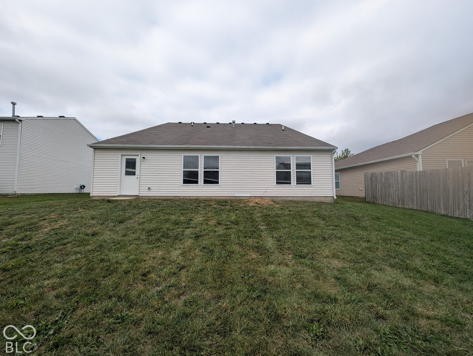 Rear exterior featuring white vinyl siding, multiple windows with white trim, and a rear entry door