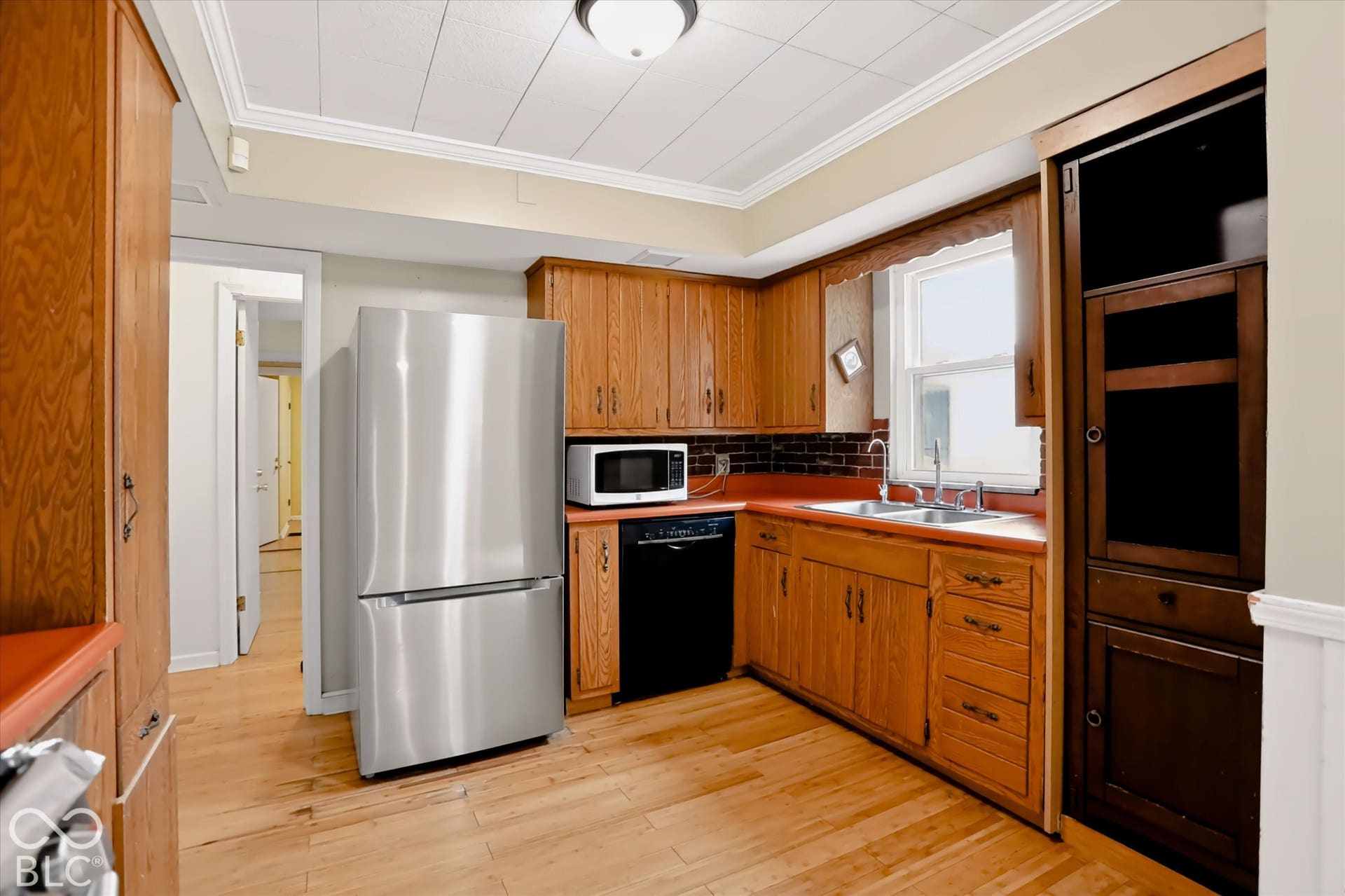 Wood-finish flooring with full-height wood cabinetry and stainless steel appliances