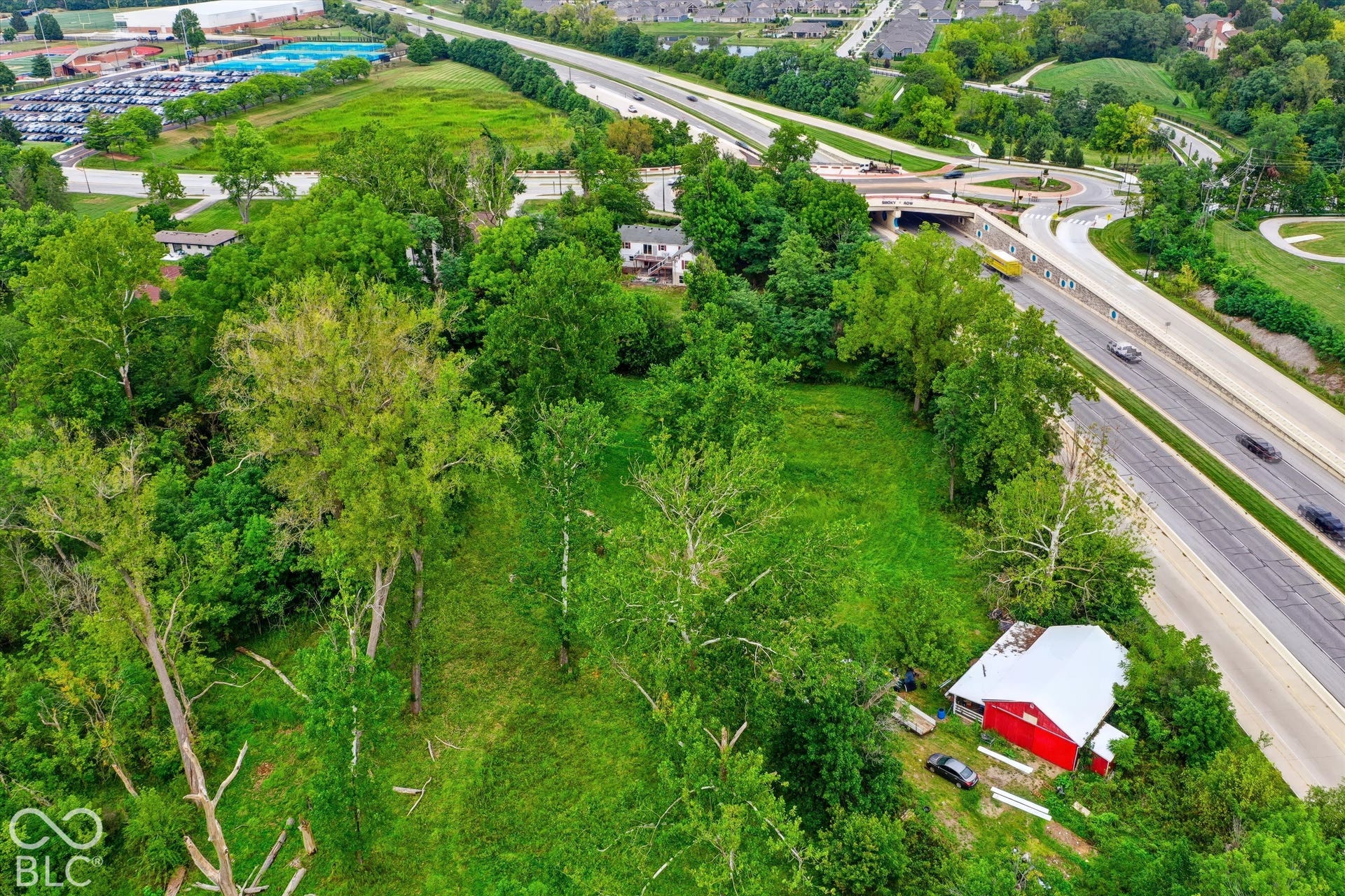 Expansive green space with mature trees, surrounded by residential properties and a multi-lane highway