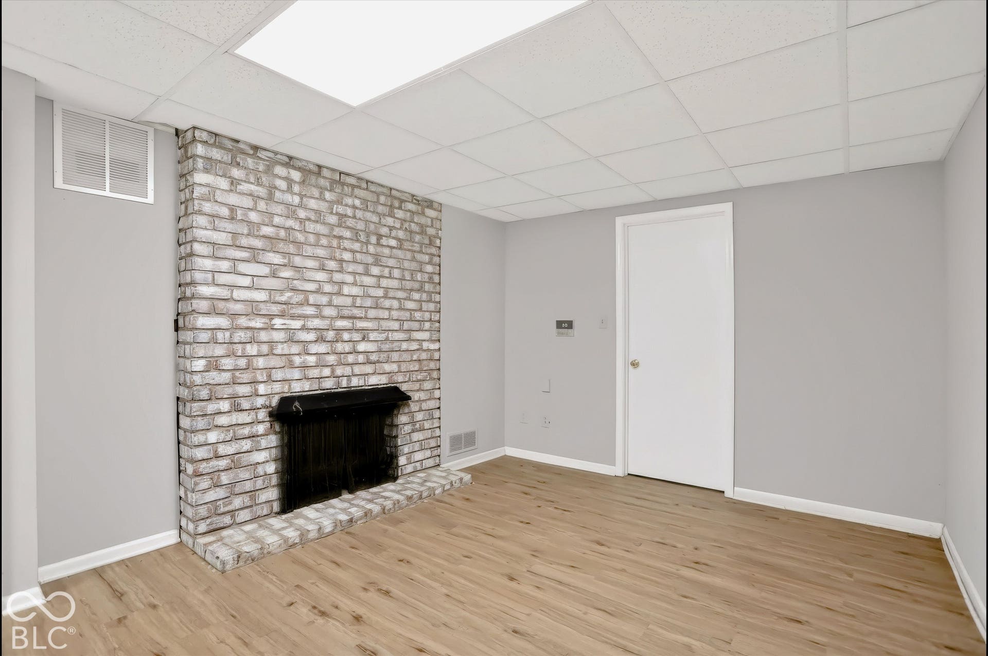 Brick fireplace with hearth, wood-finish flooring, and recessed ceiling lighting
