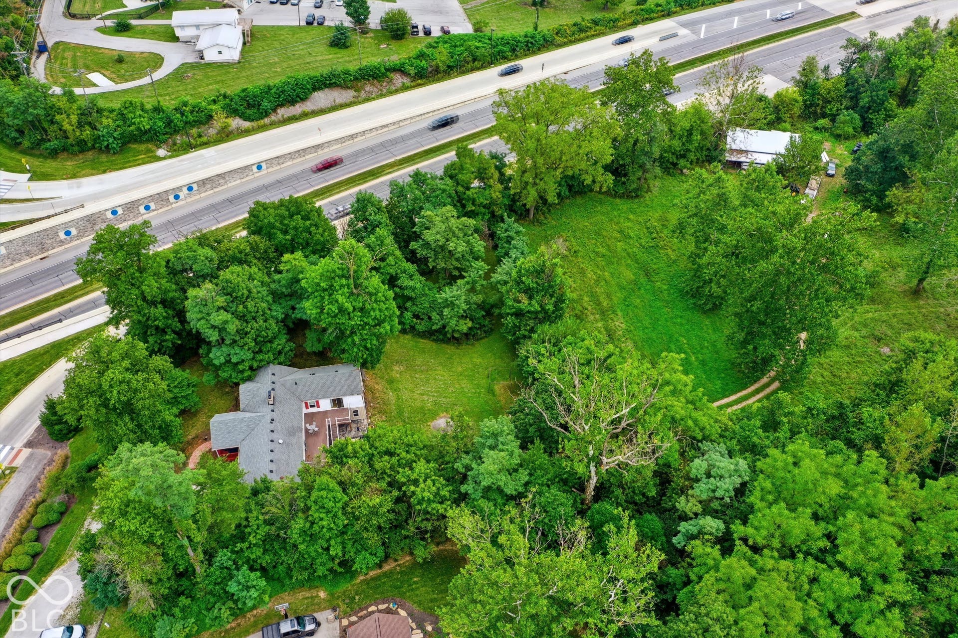 Expansive wooded lot featuring a residential structure with a gray roof and a prominent deck