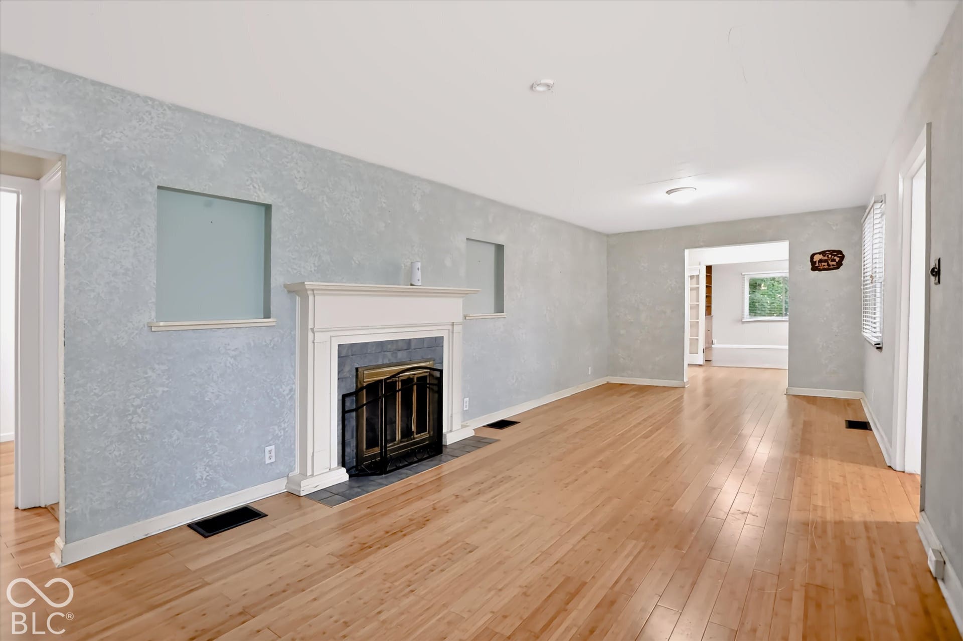 Hardwood flooring, fireplace with a mantel, tiled fireplace surround, architectural wall cutouts, and white trim