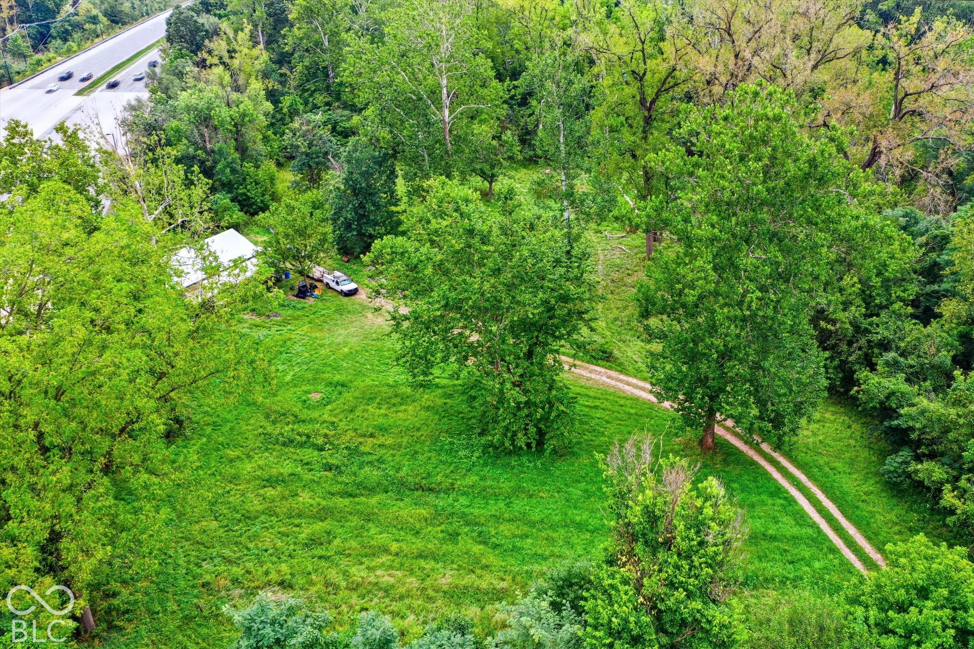 Wooded lot with a single-story structure and a gravel driveway
