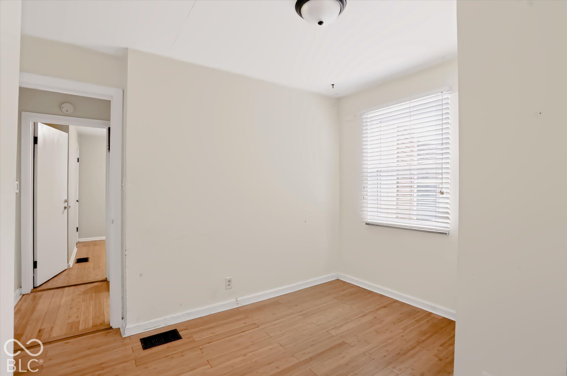 Wood-finish flooring, overhead flush-mount lighting, and window with blinds