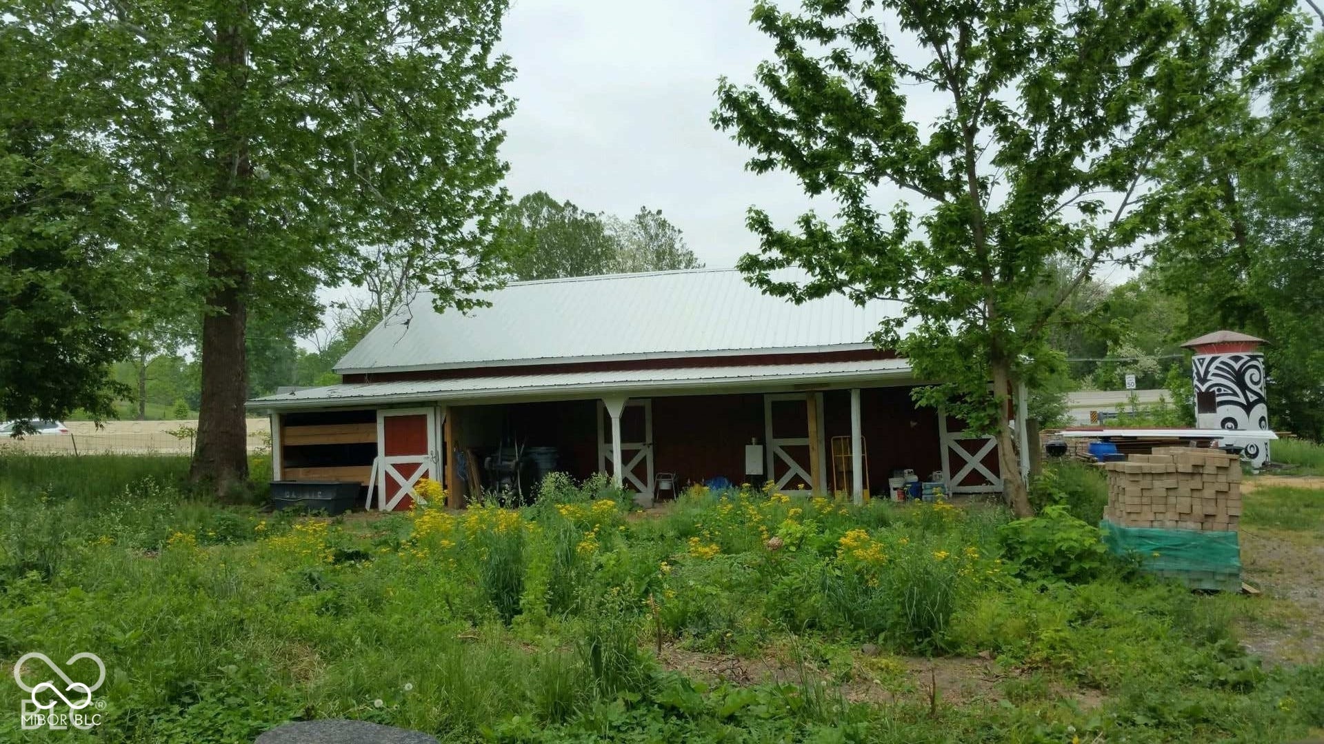 Red barn-style structure featuring a metal roof, extended porch, and white support columns