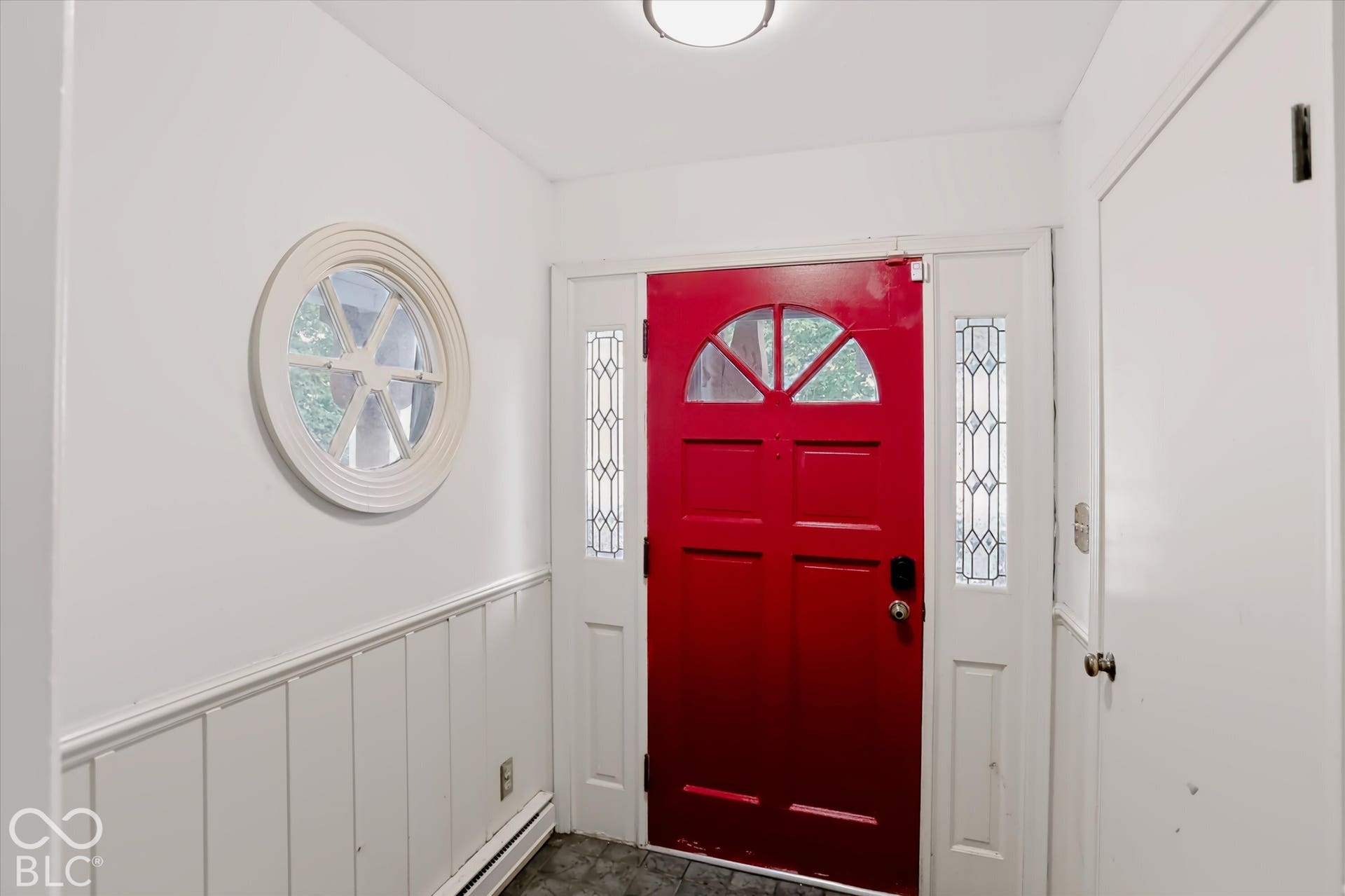 Red entry door with an arched window and leaded glass sidelights