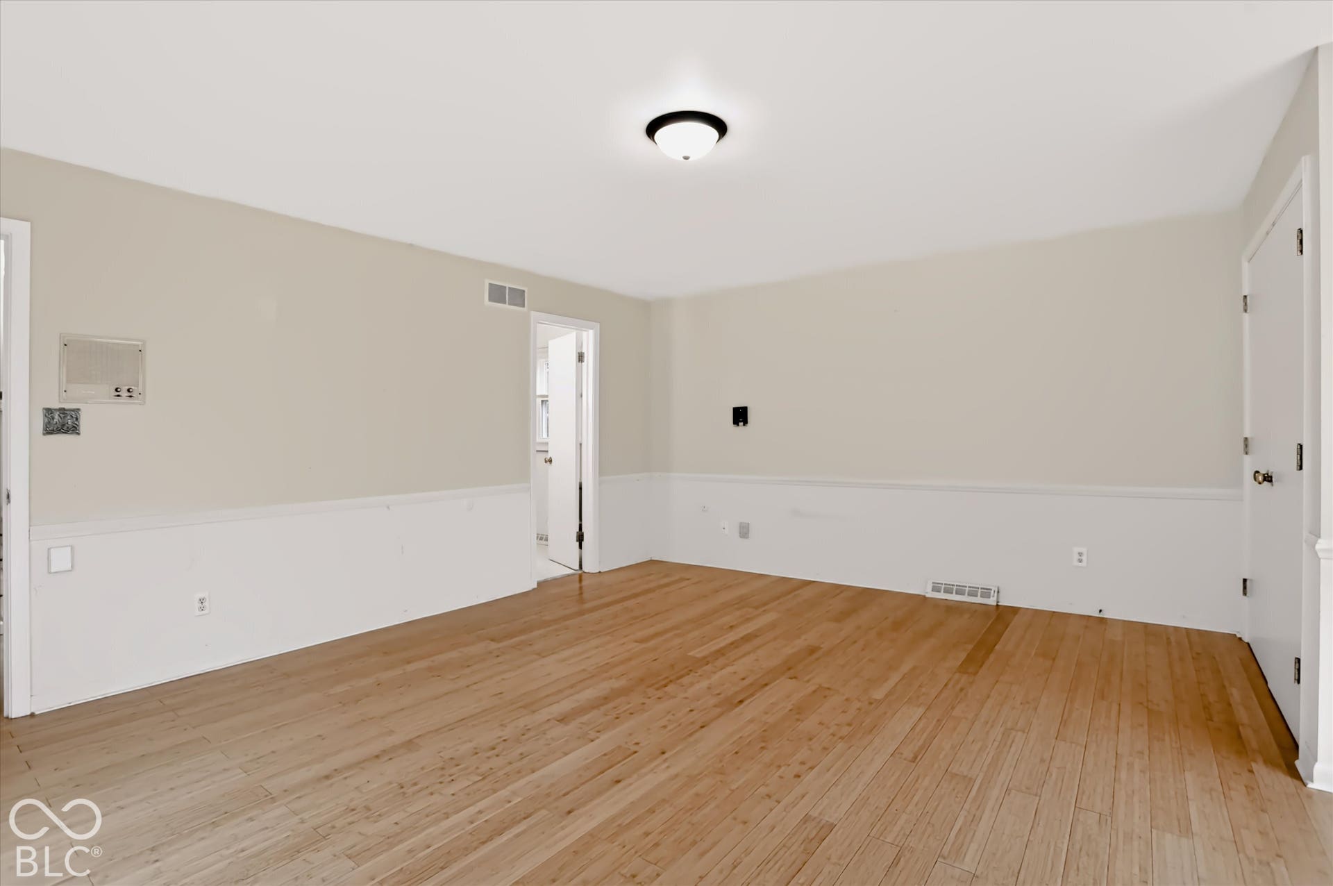 Wood-finish flooring, two-tone painted walls with wainscoting, and a ceiling-mounted light fixture