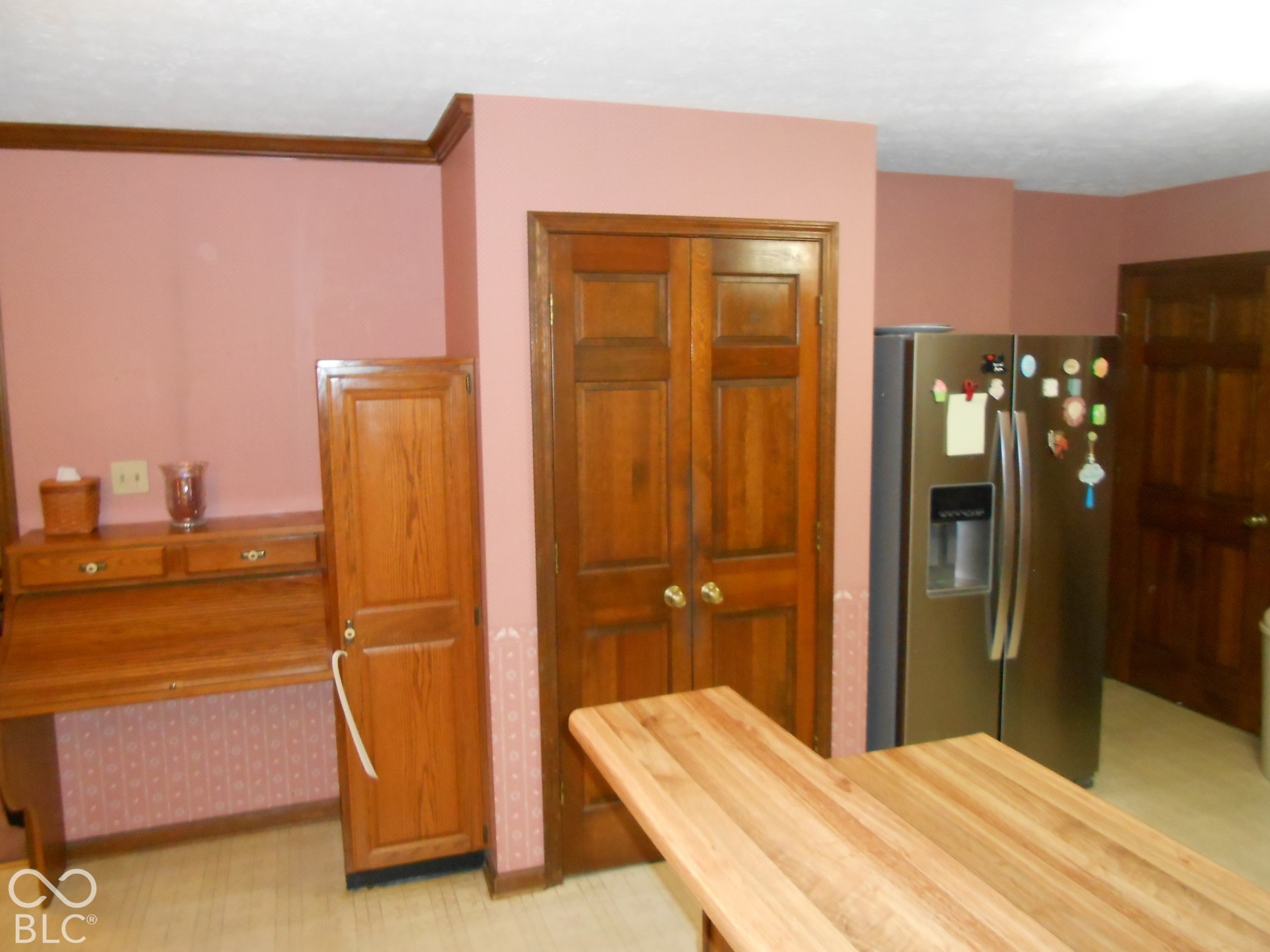 Stainless steel side-by-side refrigerator, wood cabinetry, and wood trim molding