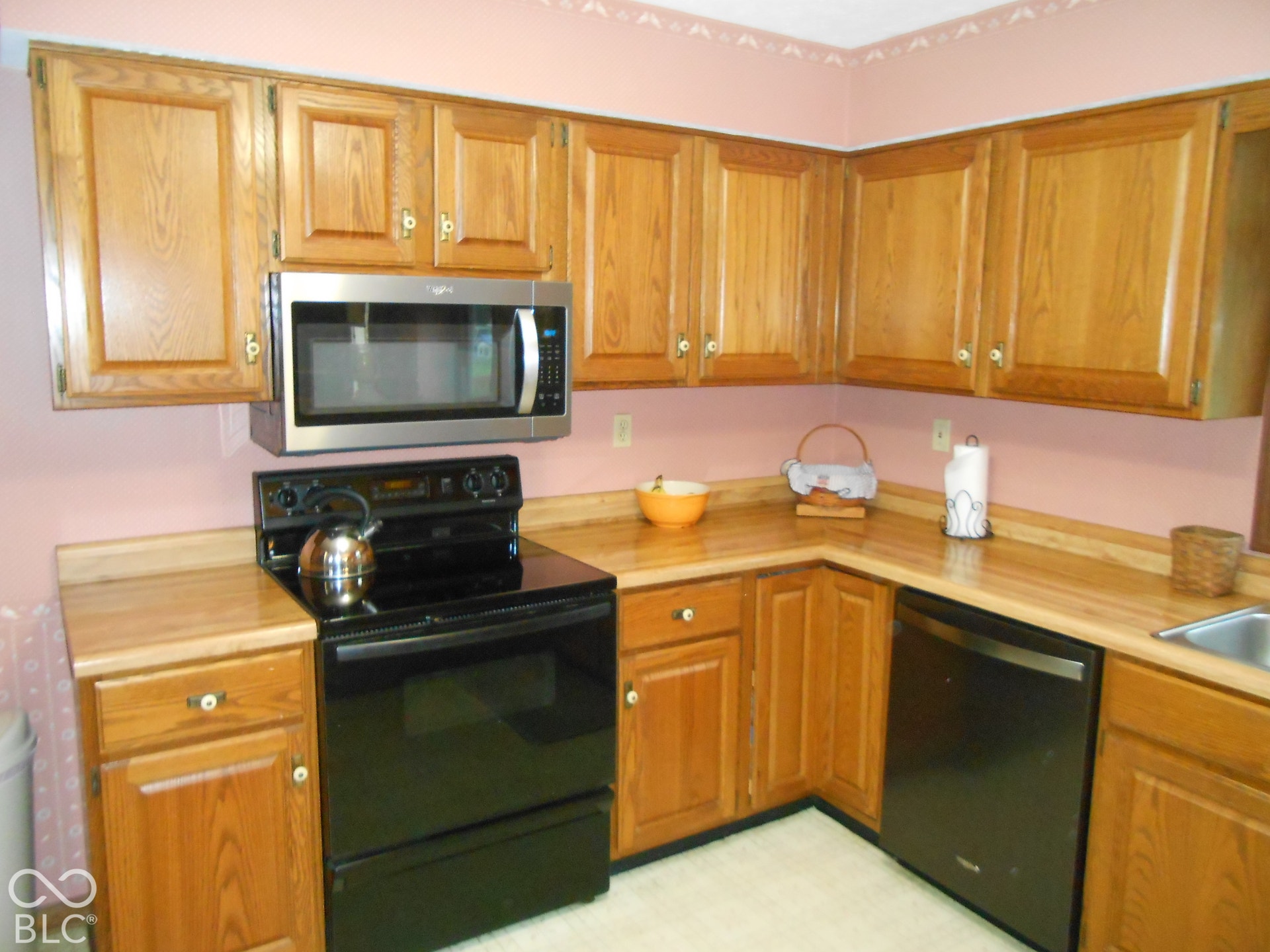 Kitchen featuring wood cabinetry, stainless steel microwave, black electric range.