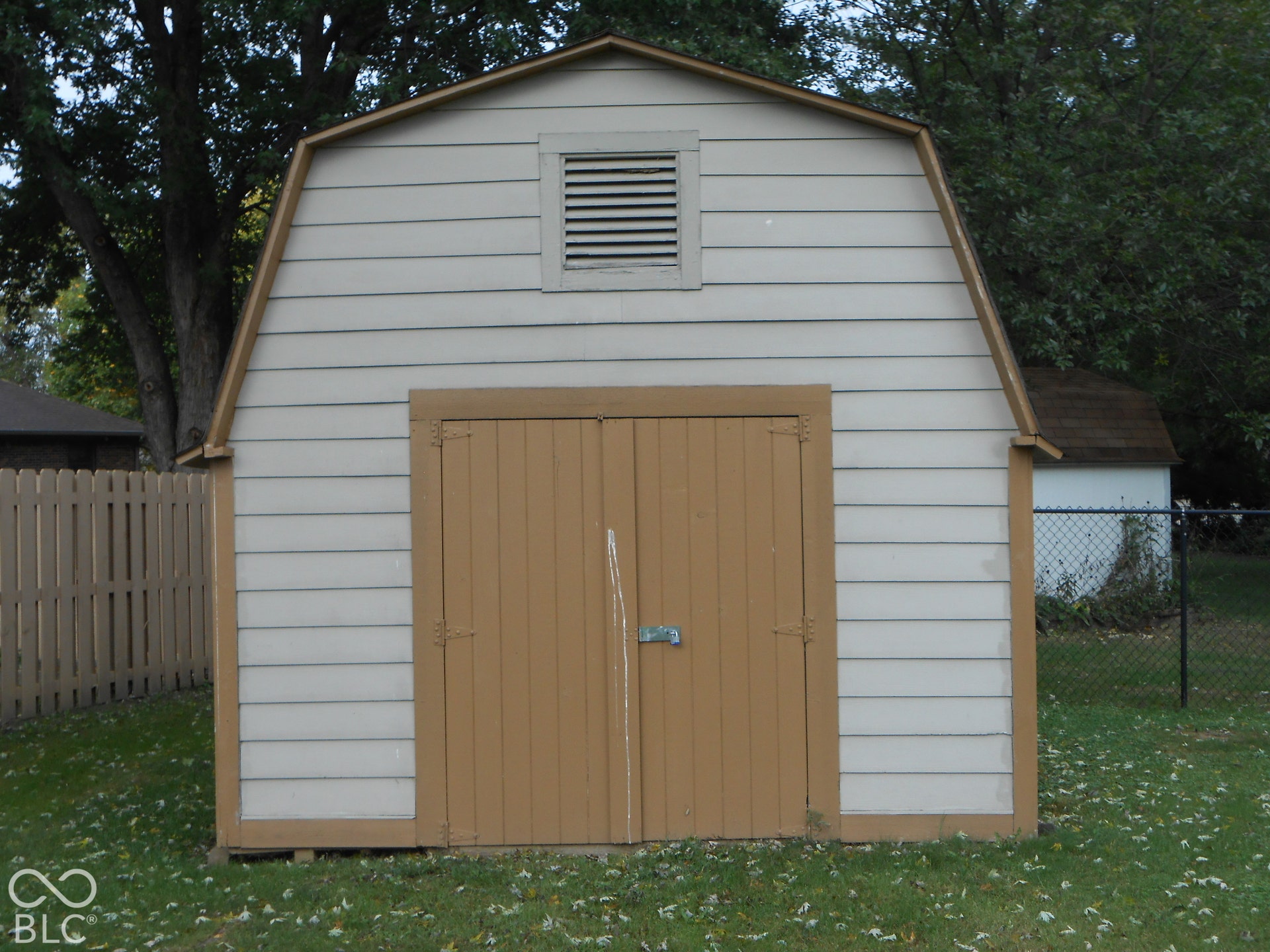 Gambrel-style shed with horizontal siding, double doors, and a louvered vent